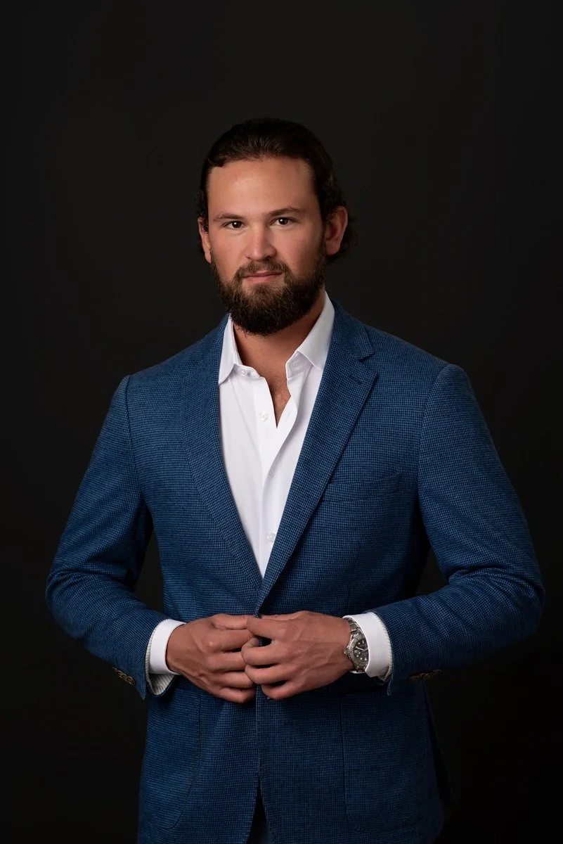 serious headshot of man in dark blue suit