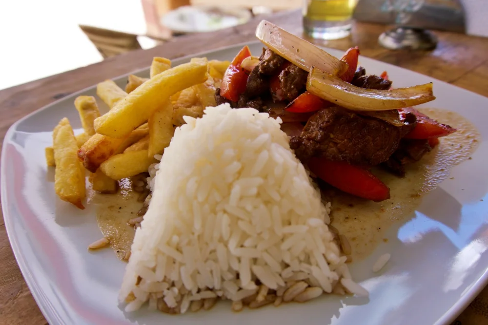 Lomo Saltado is served with papas fritas (hot chips) and rice.