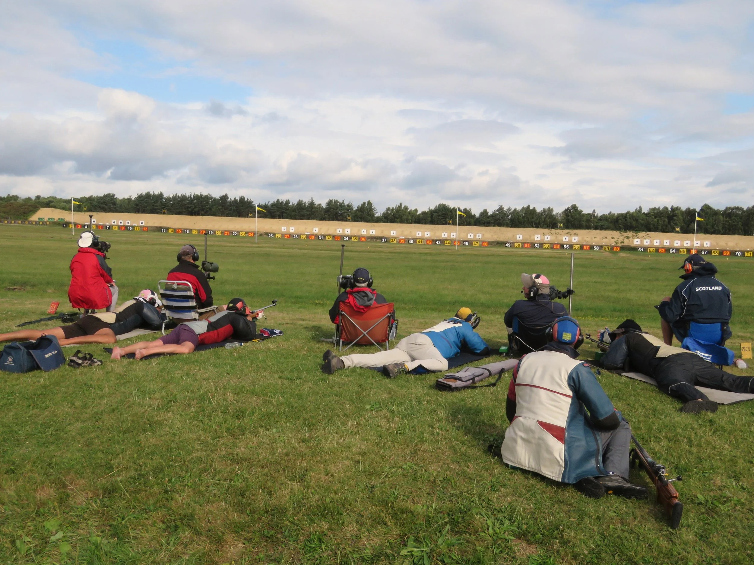 GB team in Kolapore match in typical two target format: Main Wind coach central, plotters on extreme left and right and target coaches sitting between two firers. Sandy Walker left hand firer on left target, Ian Shaw (lightblue jacket) and Bruce Logan right, plotting for right hand target.