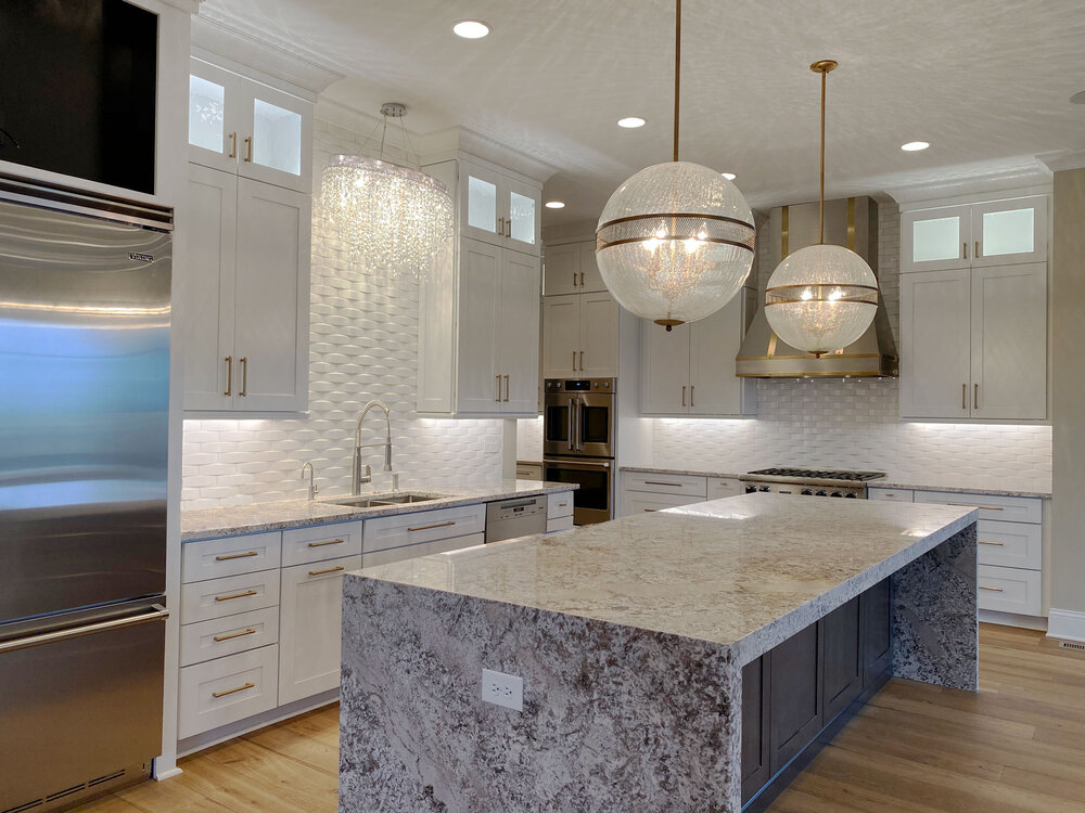 Statement pendant lights hang above a waterfall island in this contemporary kitchen.