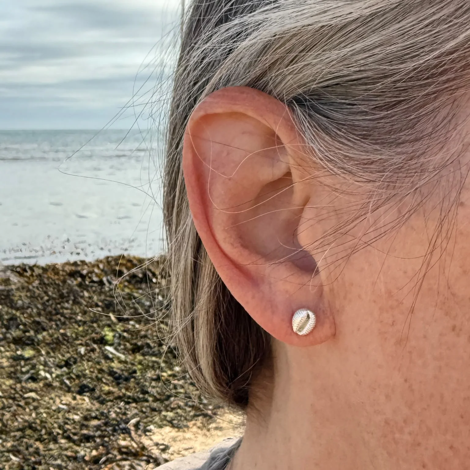 tiny-silver-cowrie-shell-stud-earring-worn.jpeg