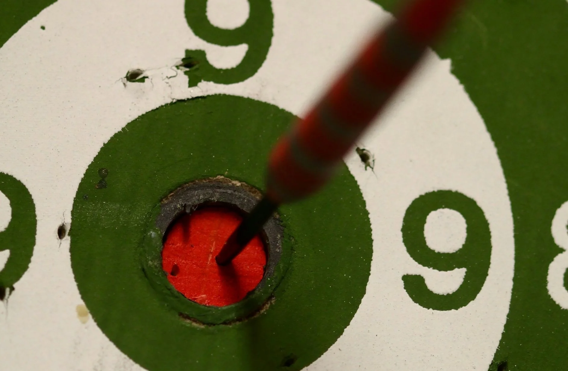 A dart in the bull's eye of an old dart board.