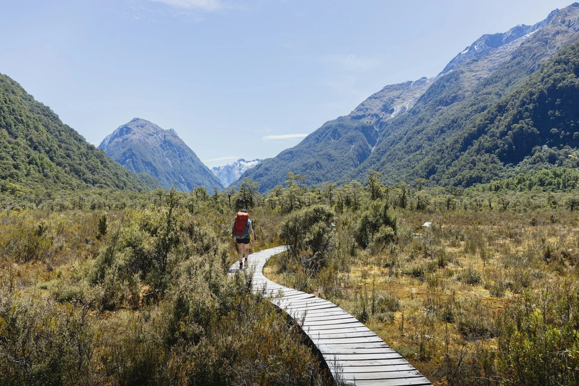 A lone hiker on a long path through steep mountains.