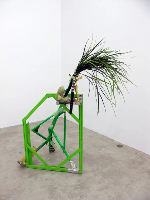 Justin Lieberman, The Green Party Monument with Bookshelf , 2011, wood, aluminum, studded belt, brass candle stick, resin, brick, pipe, frog, car, brass statue, champagne flutes, 65 x 54 x 32 in