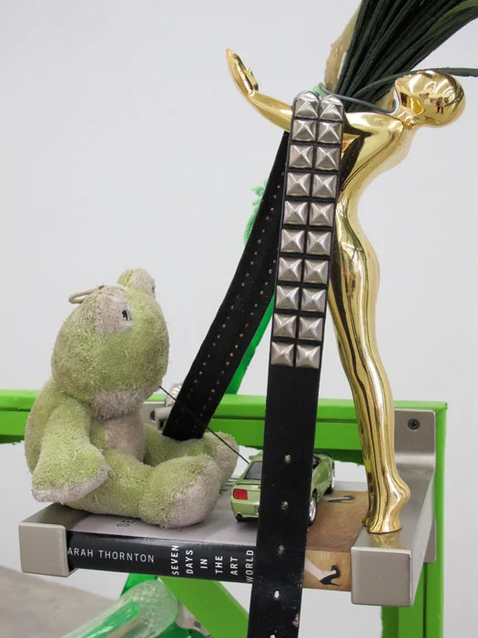 Justin Lieberman, The Green Party Monument with Bookshelf (detail), 2011, wood, aluminum, studded belt, brass candle stick, resin, brick, pipe, frog, car, brass statue, champagne flutes, 65 x 54 x 32 in