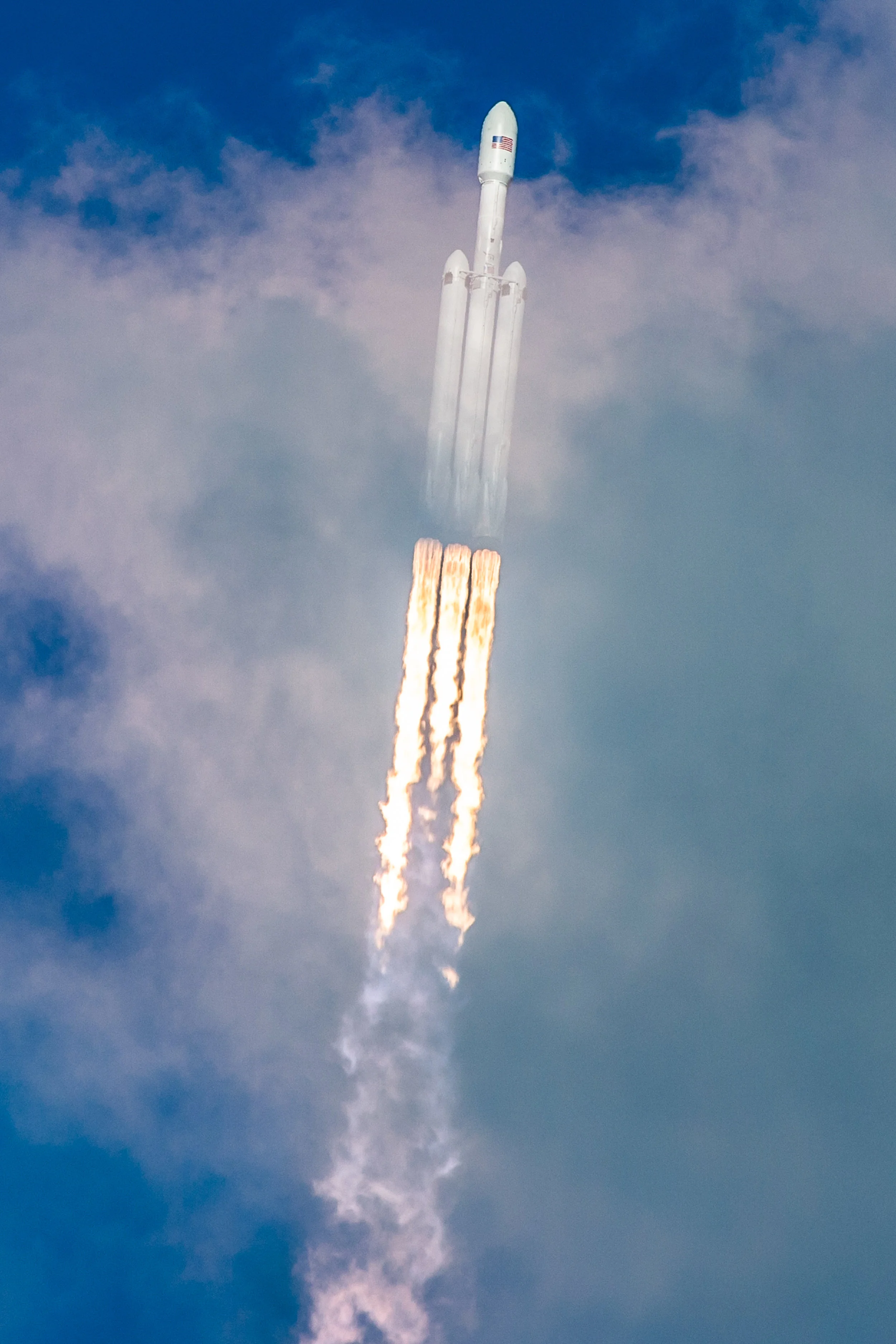 Falcon Heavy rips through the clouds during its ascent to orbit seconds after liftoff.
