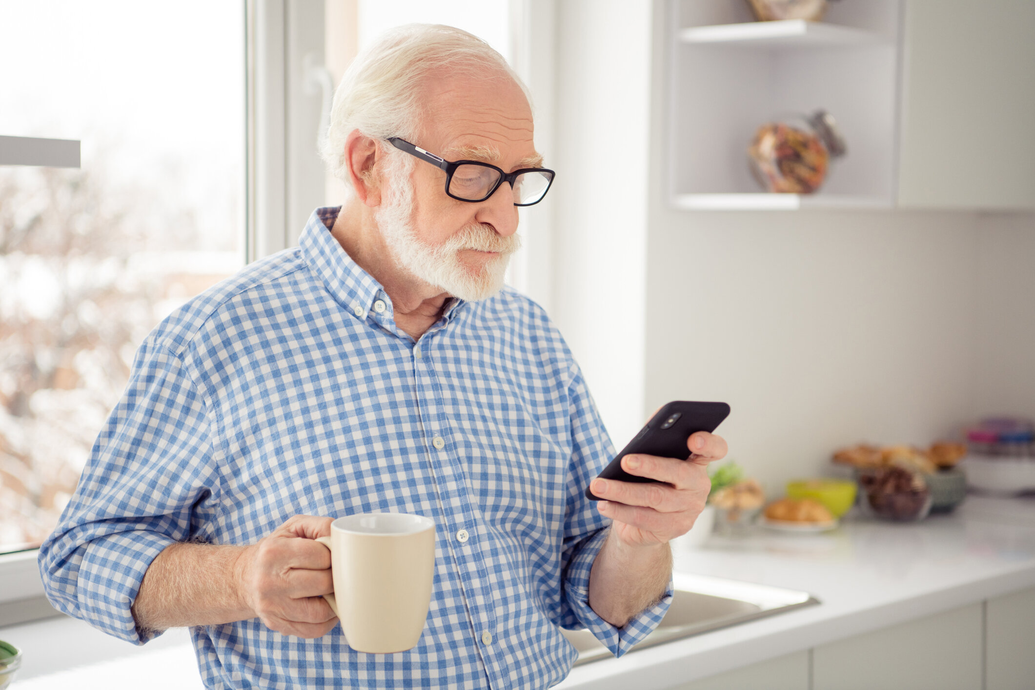 Senior with iPhone in Kitchen - iStock-1135343177.jpg