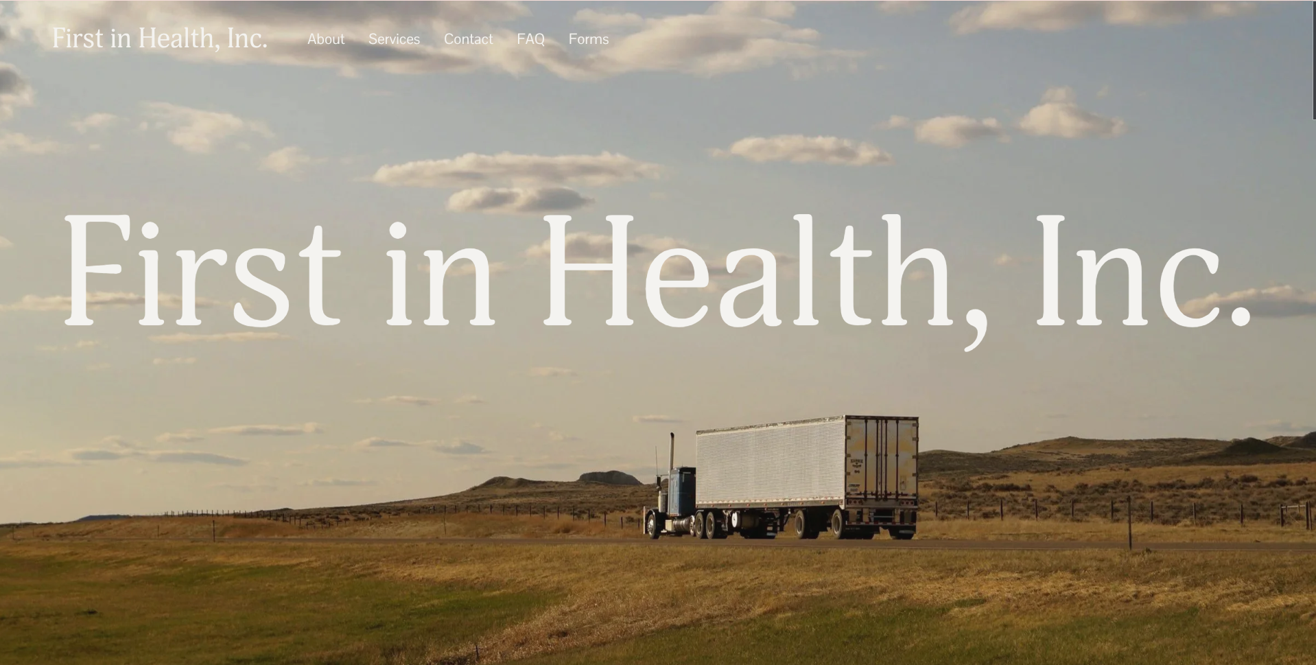 A semi-truck driving across a grassy open landscape with rolling hills under a partly cloudy sky.