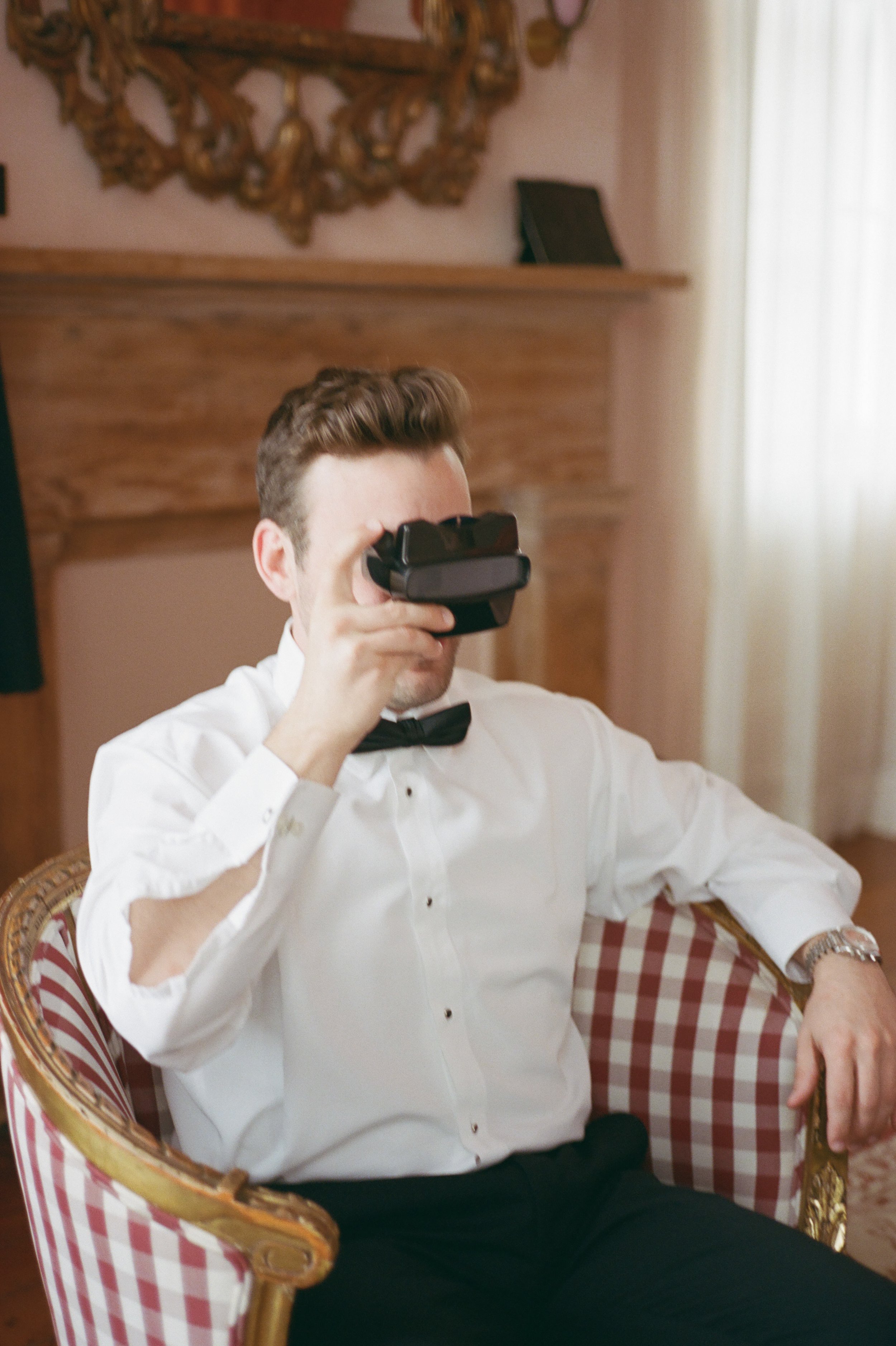 Film photo of groomsman playing with wedding favor