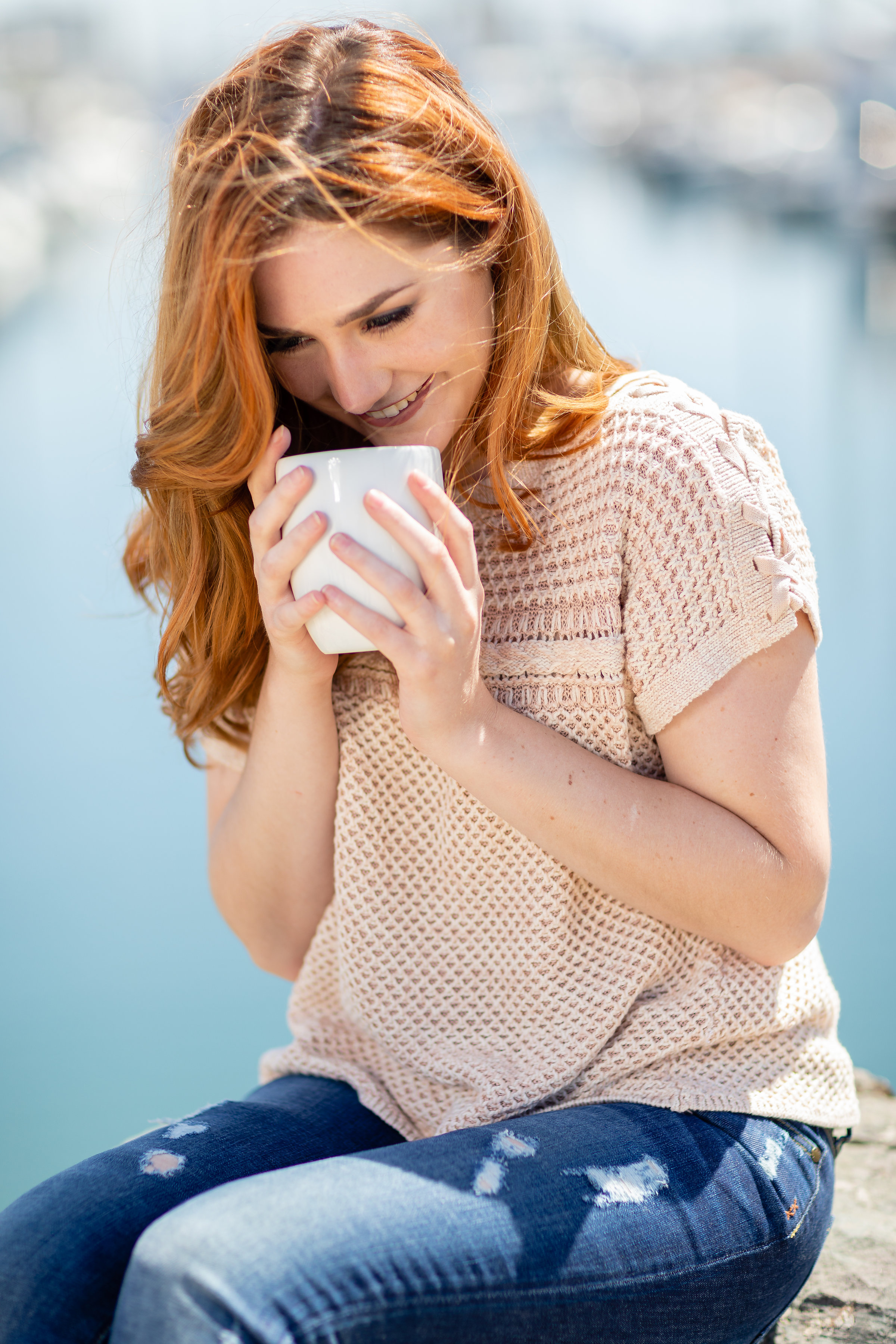 Woman smiling drinking coffee along the water.jpg