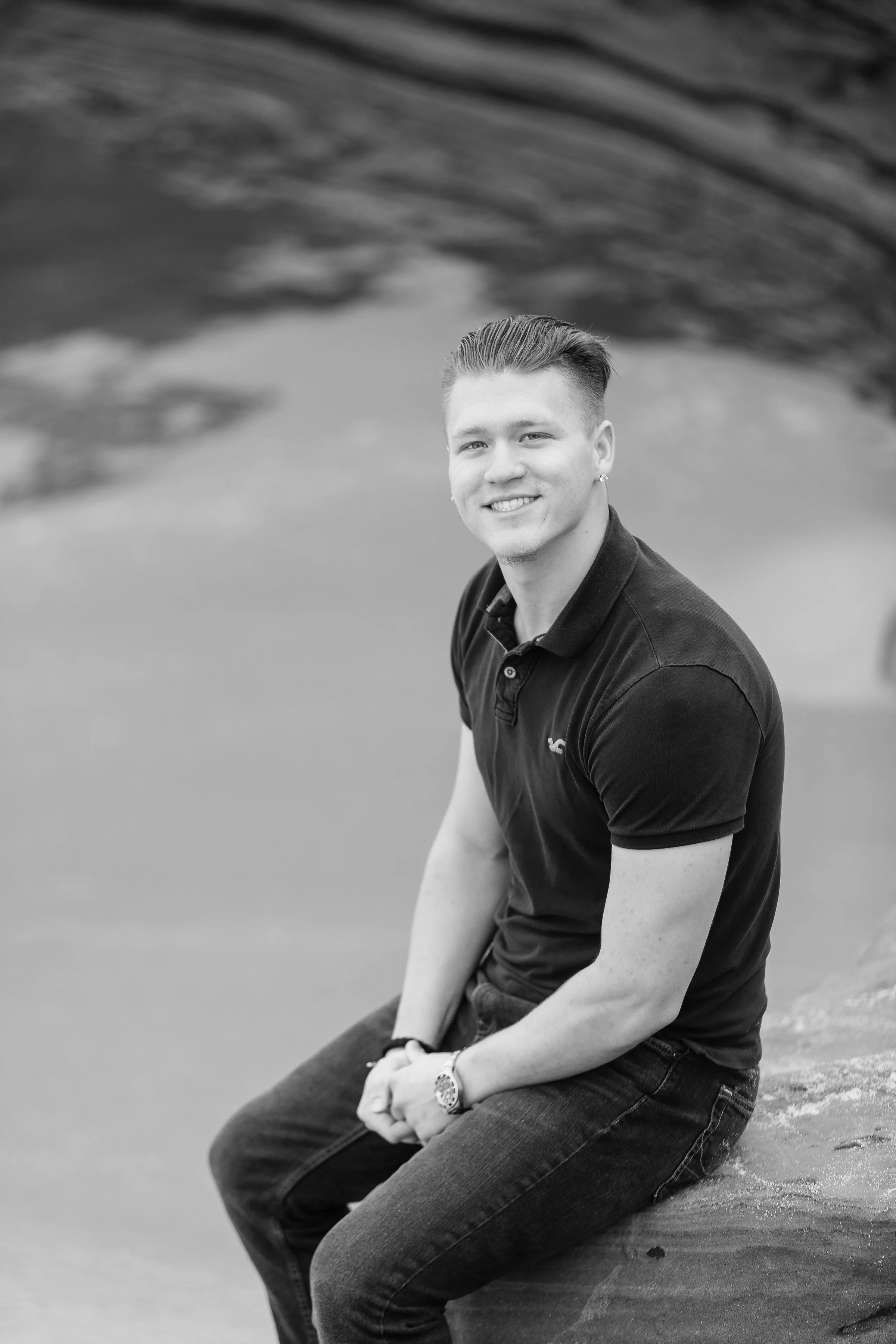 Handsome young adult male sitting on a rock in black and white.jpg