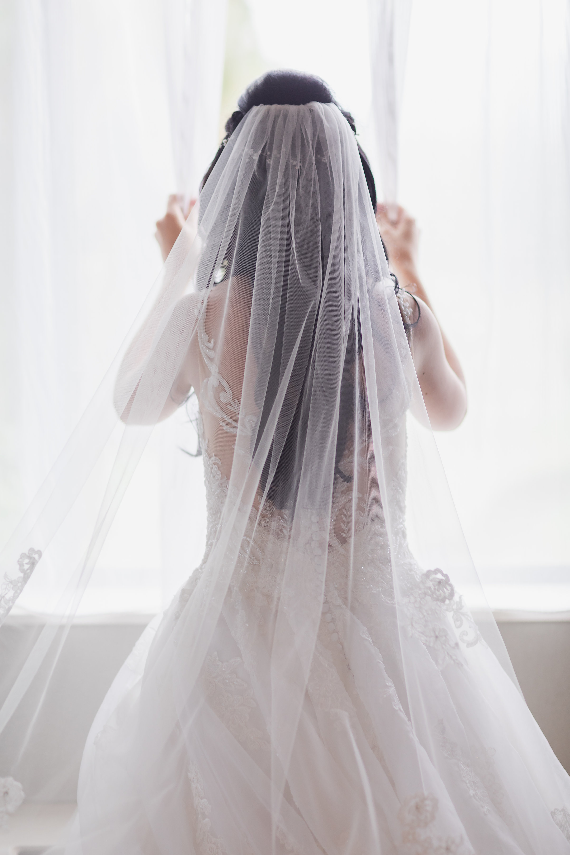 Bride Getting Ready Looking out Window with Veil.jpg