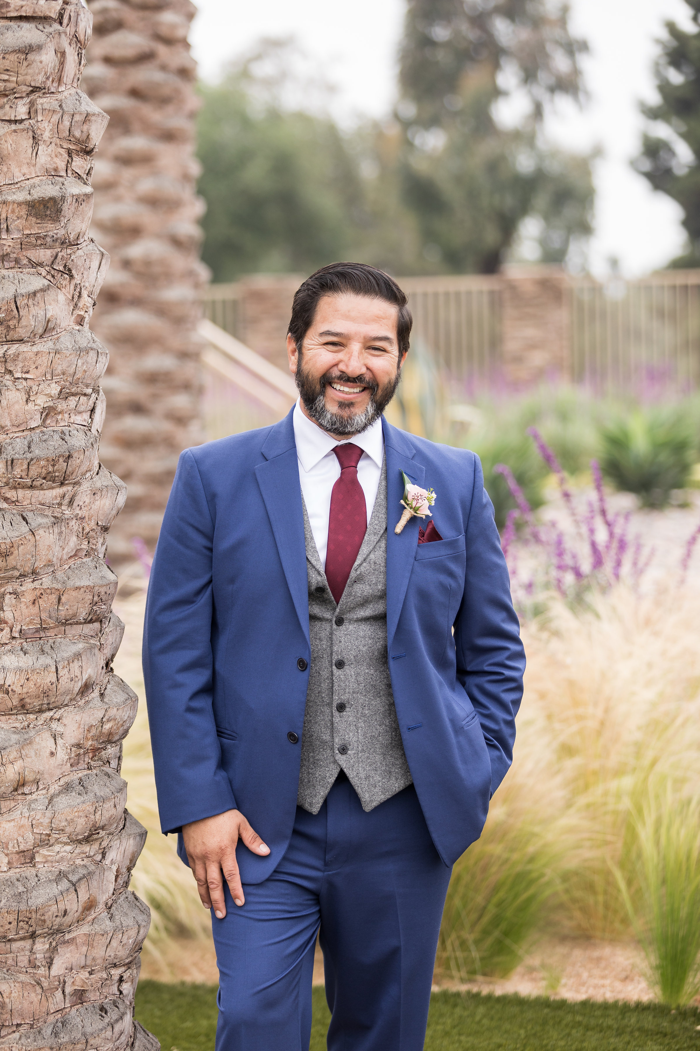 Photo of the handsome groom smiling next to a palm tree in his blue 2 piece wedding suit.jpg