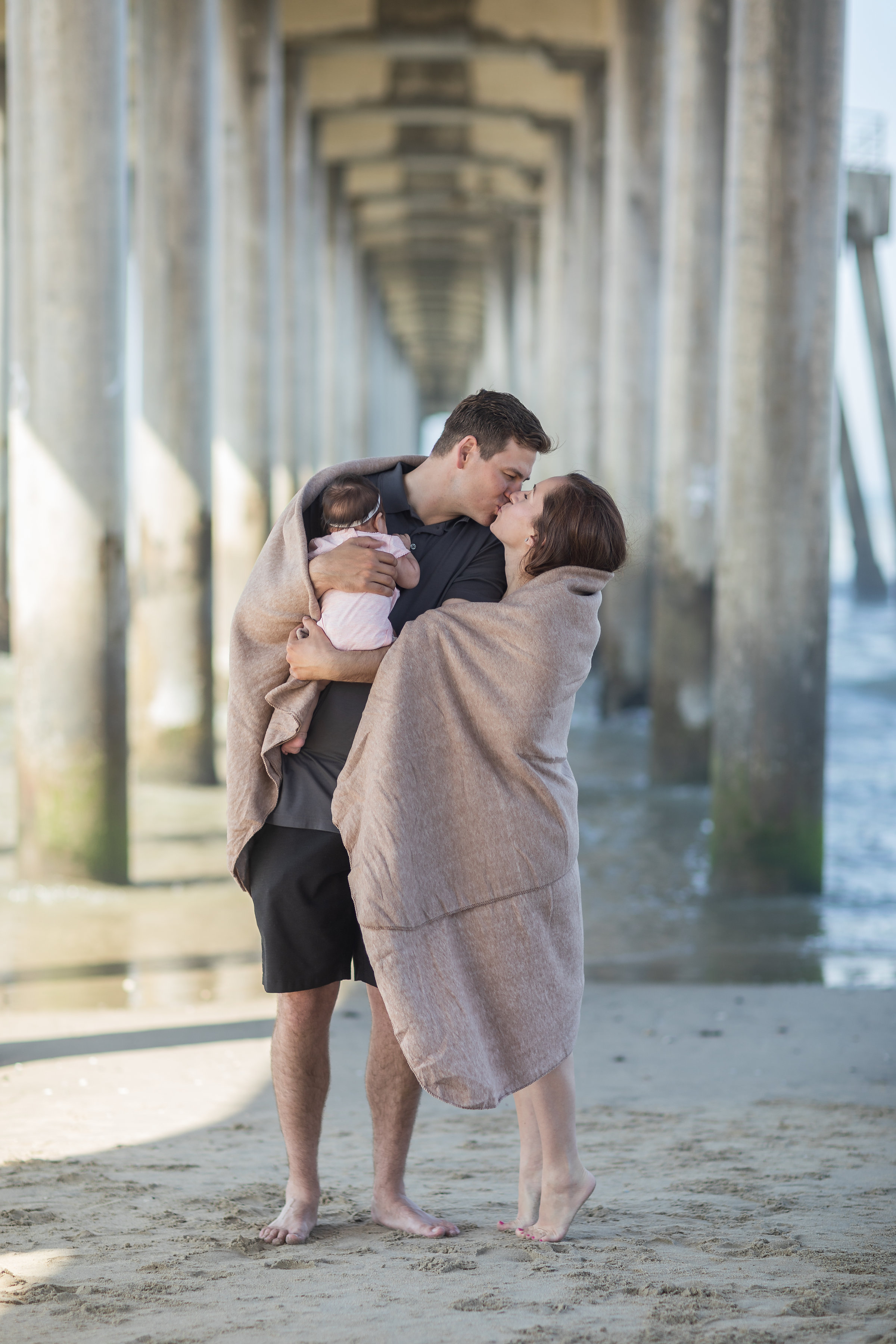 Family of 3 Pic under the Huntington Beach Pier Wraped in Blanket.jpg
