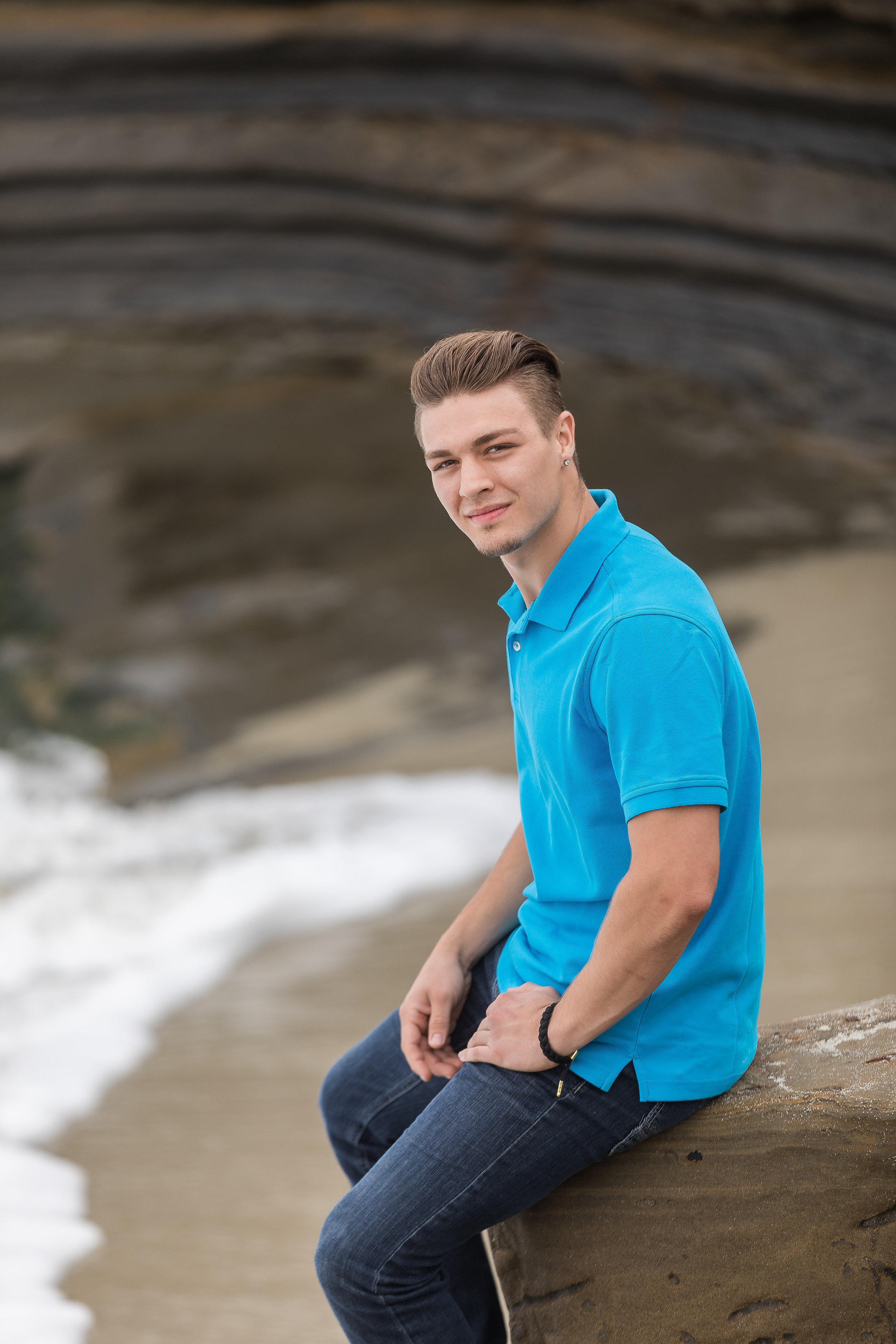good looking young man sitting on a beach rock in a blue shirt.jpg