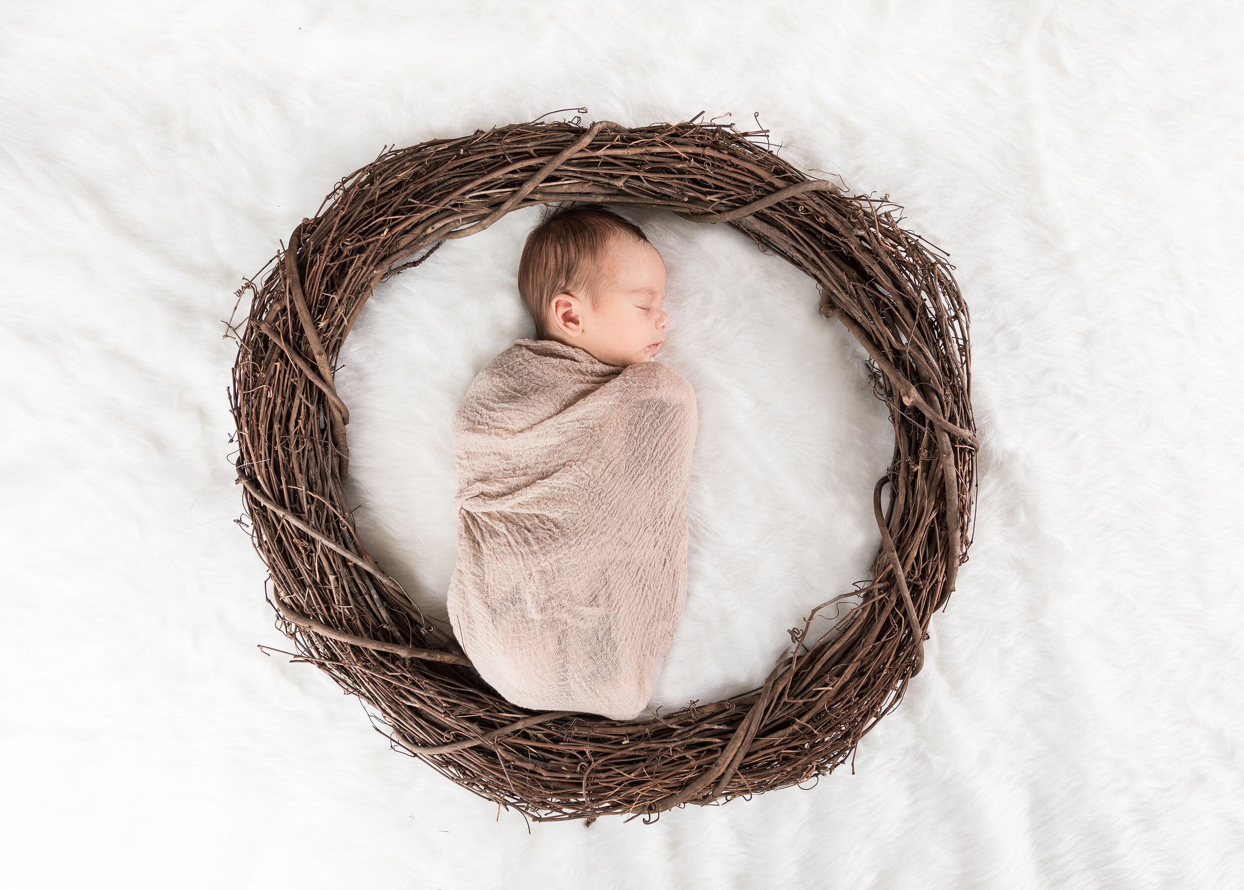 Little angel sleeping in a wreath with a white fur background james korin photography.jpg