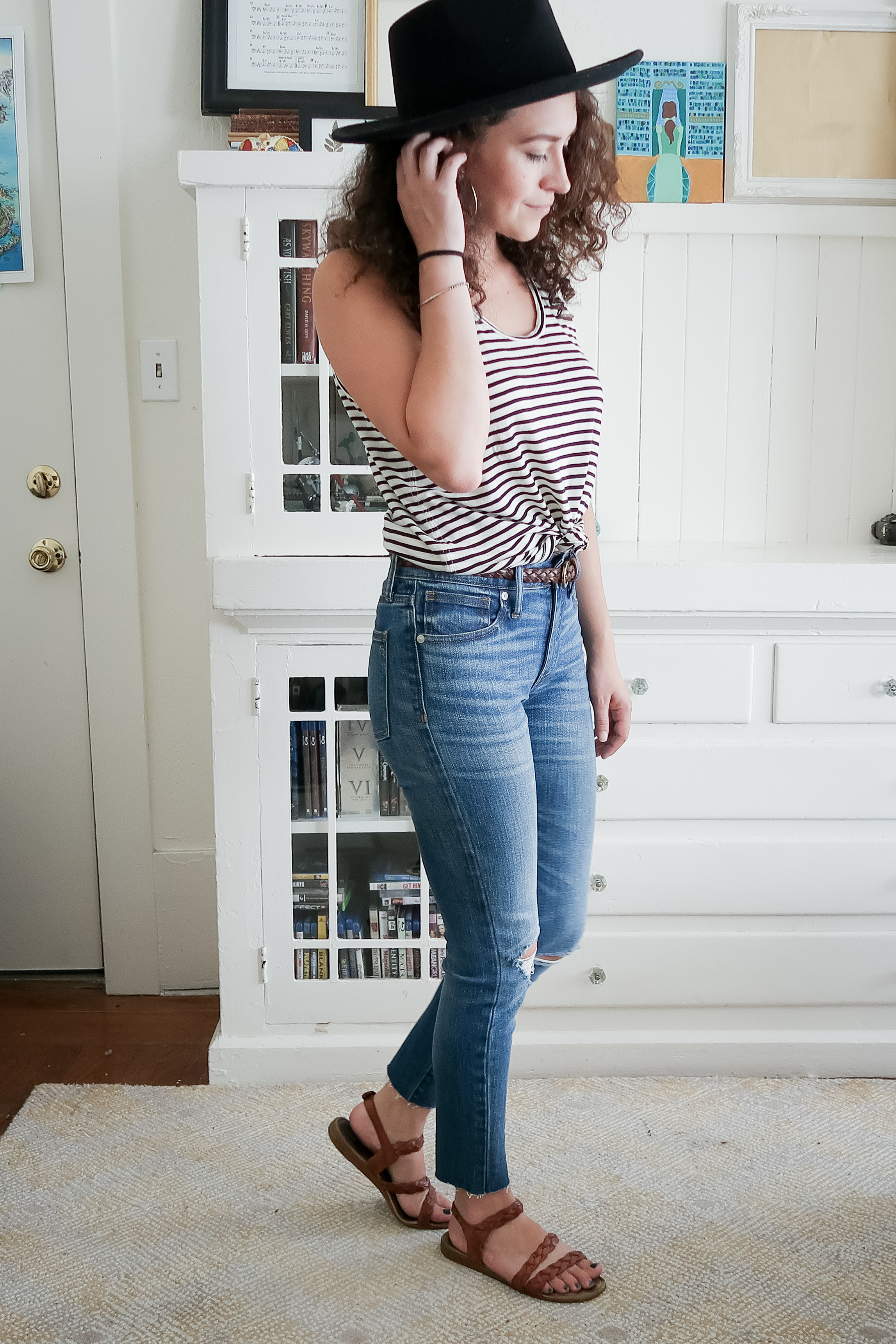 10 pieces, 10 outfits -- a stripe tank top styled with high rise distressed jeans from madewell, braided sandals and a black wide brimmed hat