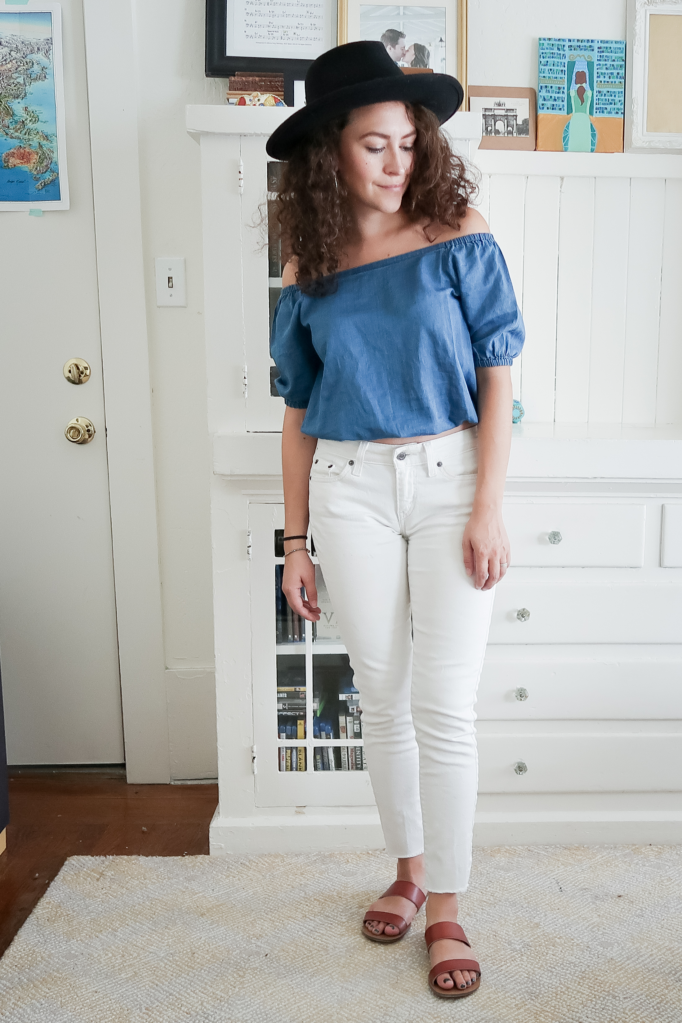 10 pieces, 10 outfits -- white levis skinny jeans worn with a bright indigo off the shoulder top from madewell, brown leather slide sandals and a black hat