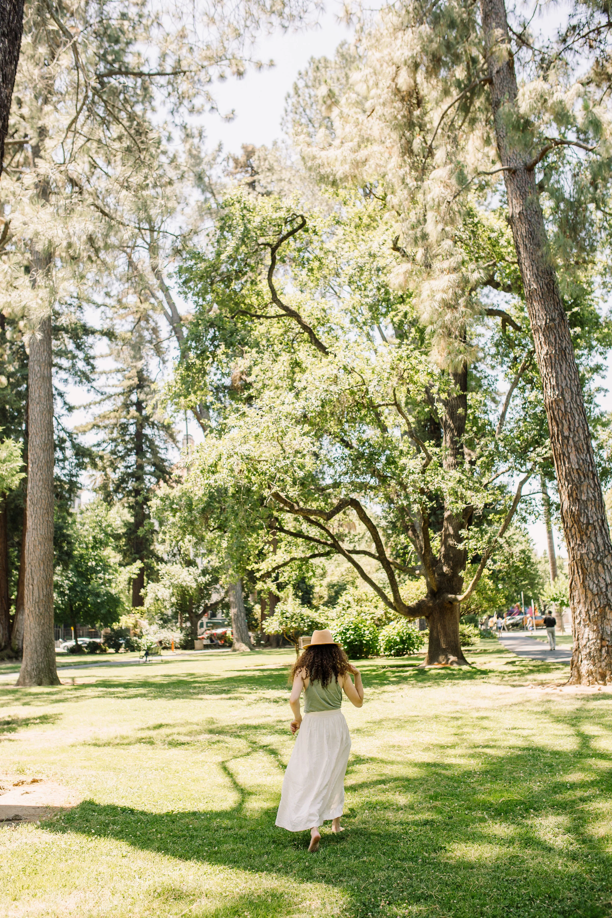 summer curly hair style:wearing a hat with curly hair - summer picnic in the park outfit: wearing sage green tank top from madewell and button up midi skirt from urban outfitters purchased secondhand on poshmark - sacramento, california - tinted-green.com - photos by sarah akiyama