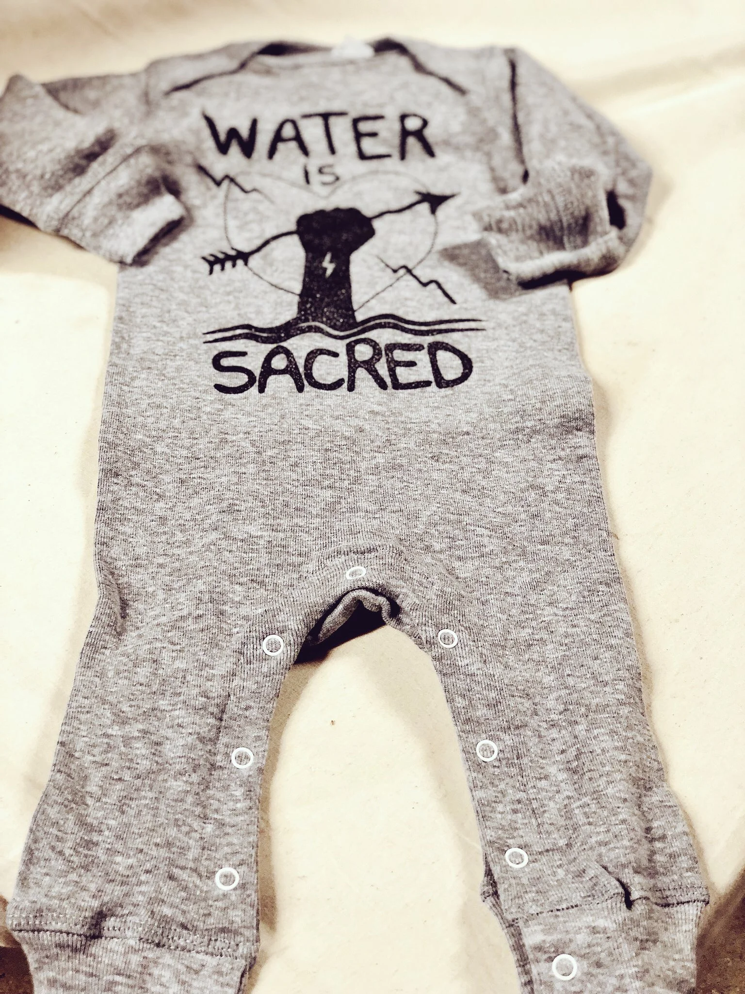 "Water is Sacred" Baby Long Legged Baby Rib Bodysuit by Christi Belcourt