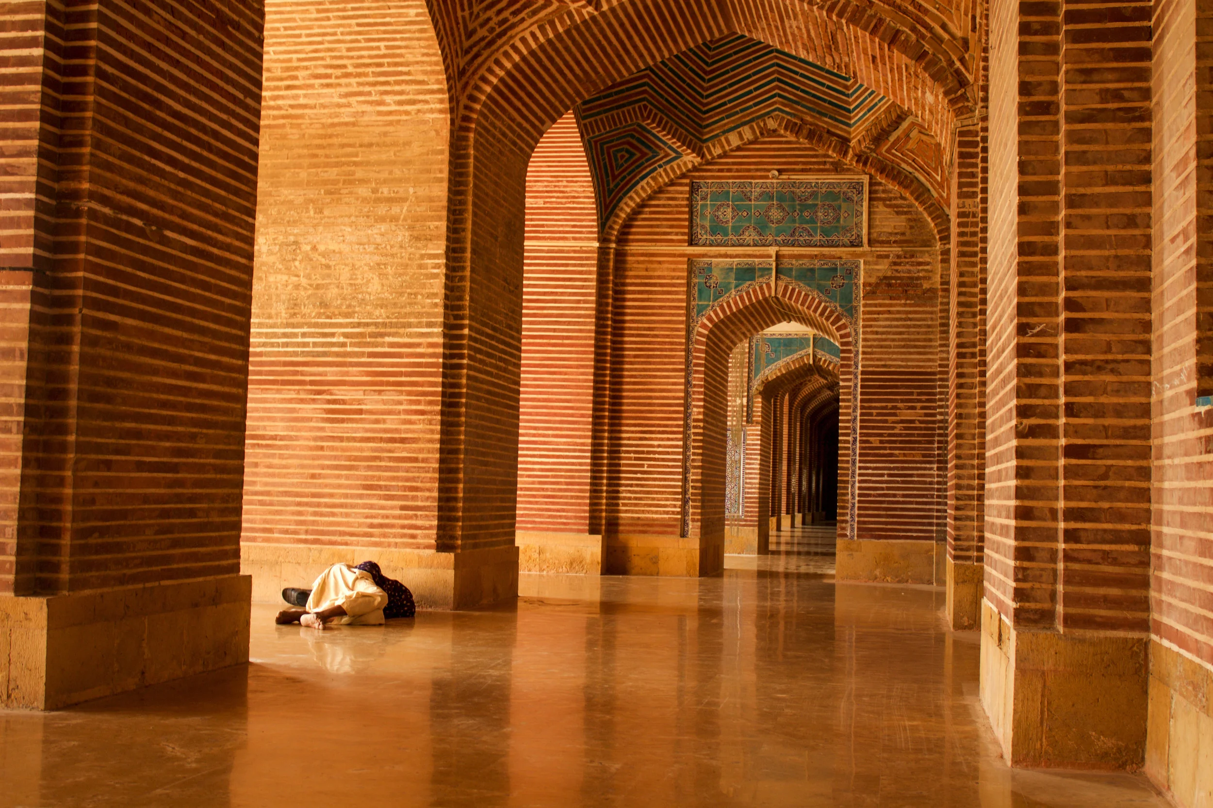A man naps in the relative shade of one of the Shah Jahan Masjid's side corridors off of the main courtyard (photo by Olivia Curl)