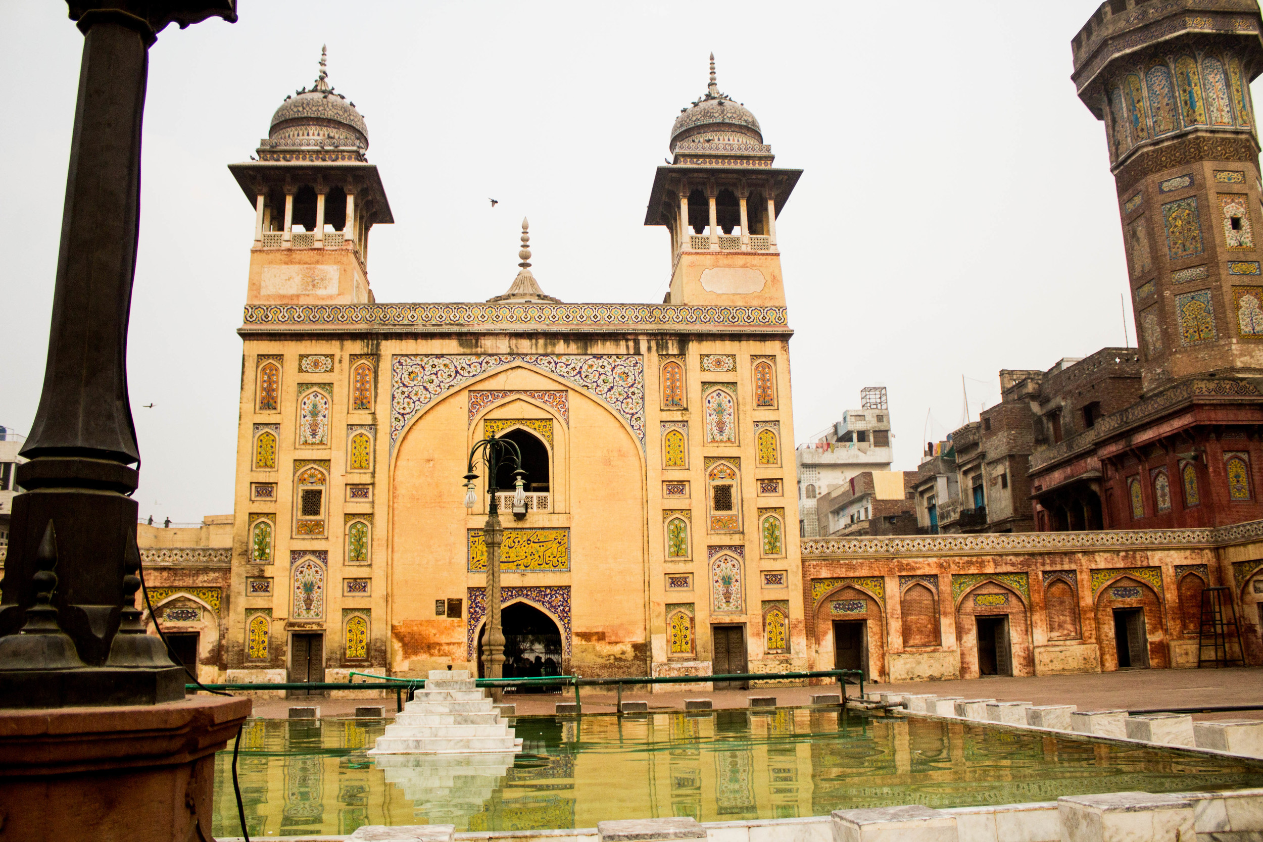 The faience tile work of the Wazir Khan Masjid reflects in the mosque courtyard's fountain pool. 