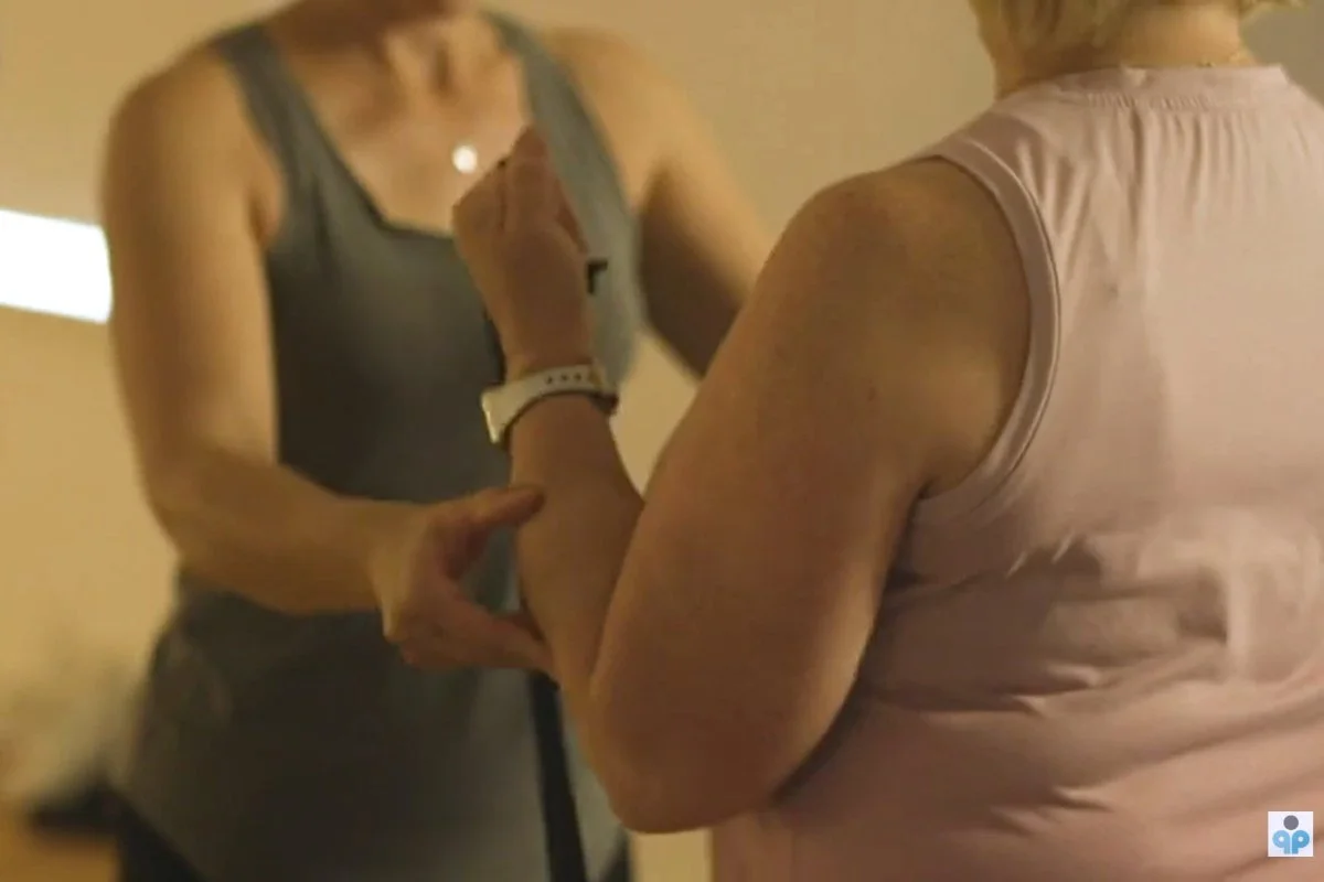 A physio helps a woman use fitness bands during senior fitness classes at Prospect, Adelaide.