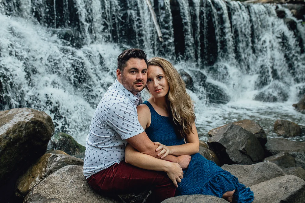 engaged-bride-and-groom-sitting-by-waterfall.jpg