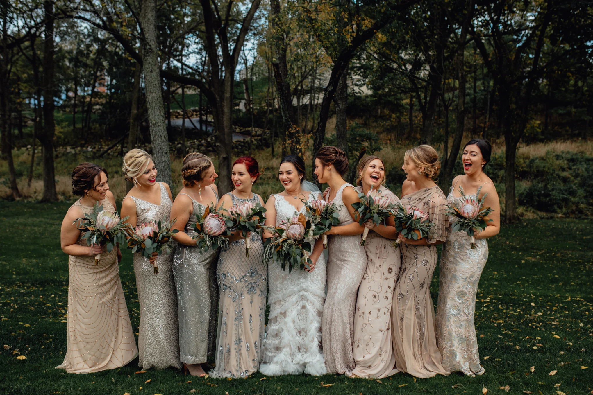 bridesmaids laughing with bouquets in grass