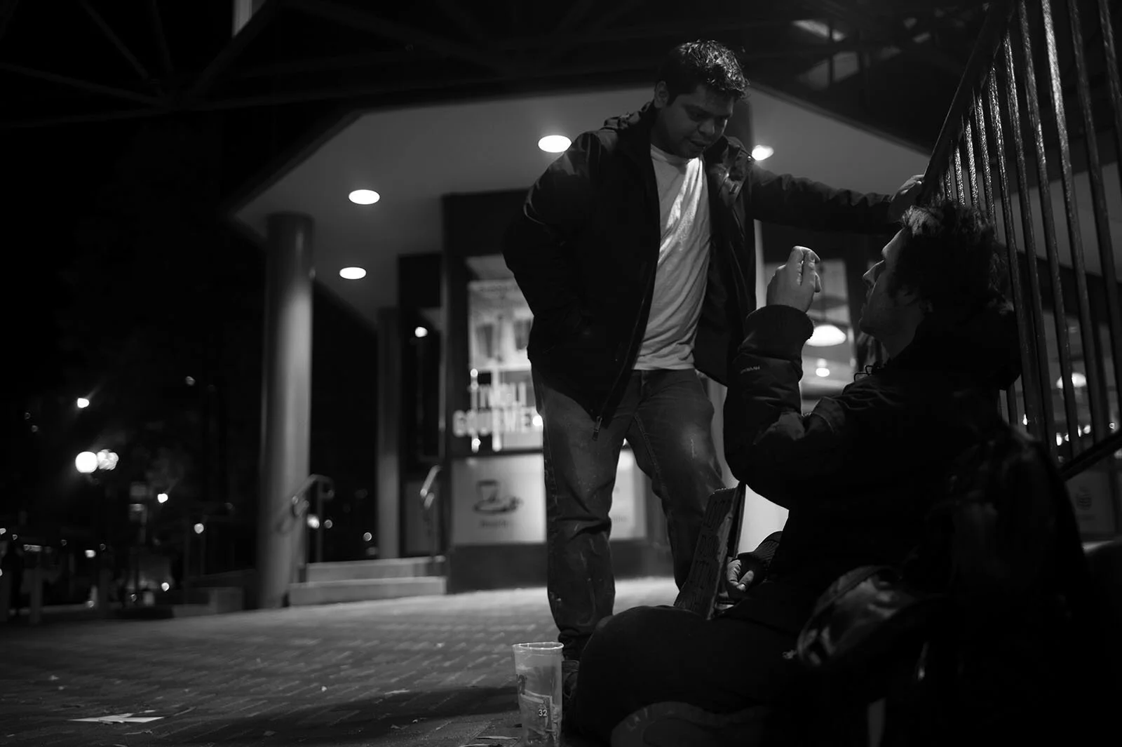 A regular visitor, who has previously notified Kenyon of employment opportunities at his job, stops to talk at the Ballston Metro station Nov. 23. He discusses logistics, the hiring process, and answers Kenyon’s questions before leaving him some cha…