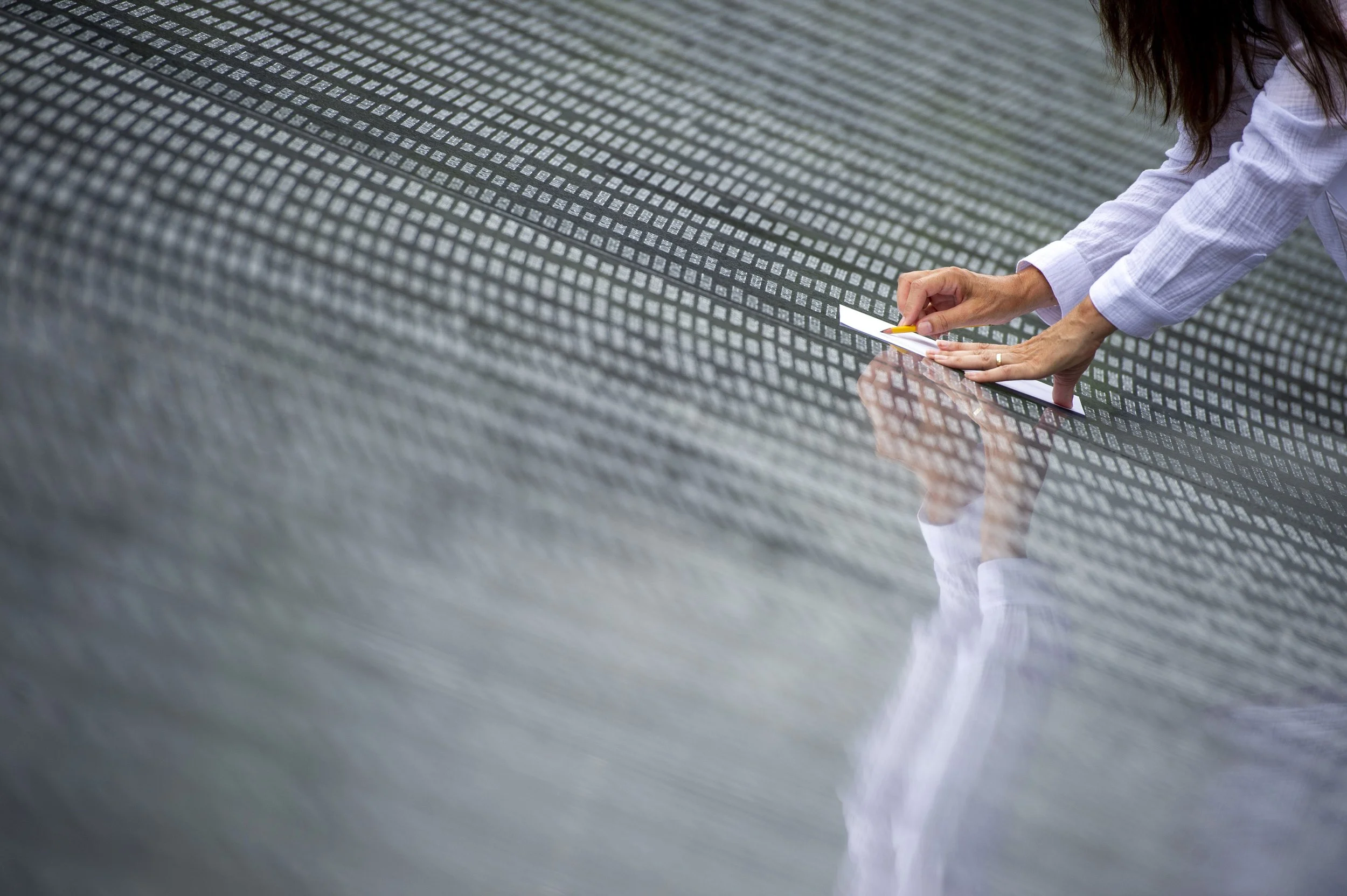  A  woman etches a name on The Wall of Remembrance, an addition to the Korean War Veterans Memorial that features the names of 36,574 Americans and more than 7,200 members of the Korean Augmentation to the U.S. Army, who died while protecting South K