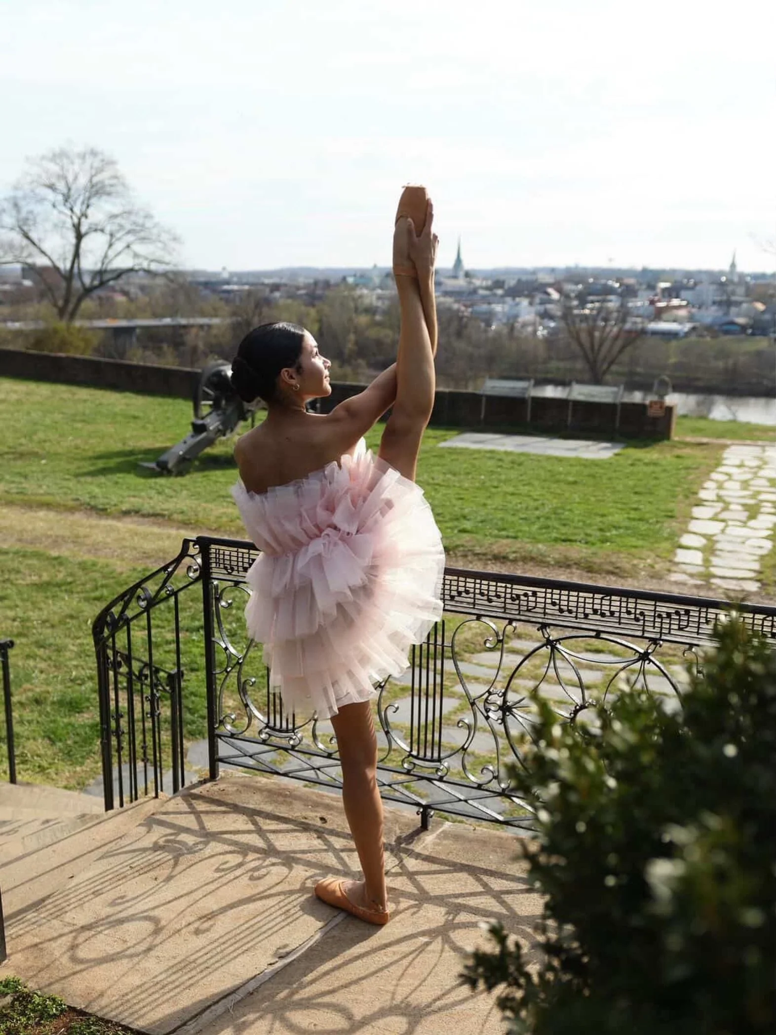 🪷

#browngirlsdoballet #brownballerina #dancephotography 

🩰: @laurenmarie.ballet 
📸: @jason_b75 

Image Description: Dancer stands outside by a black railing and is holding her leg in the air. She is wearing a pink tulle dress and pointe shoes. I