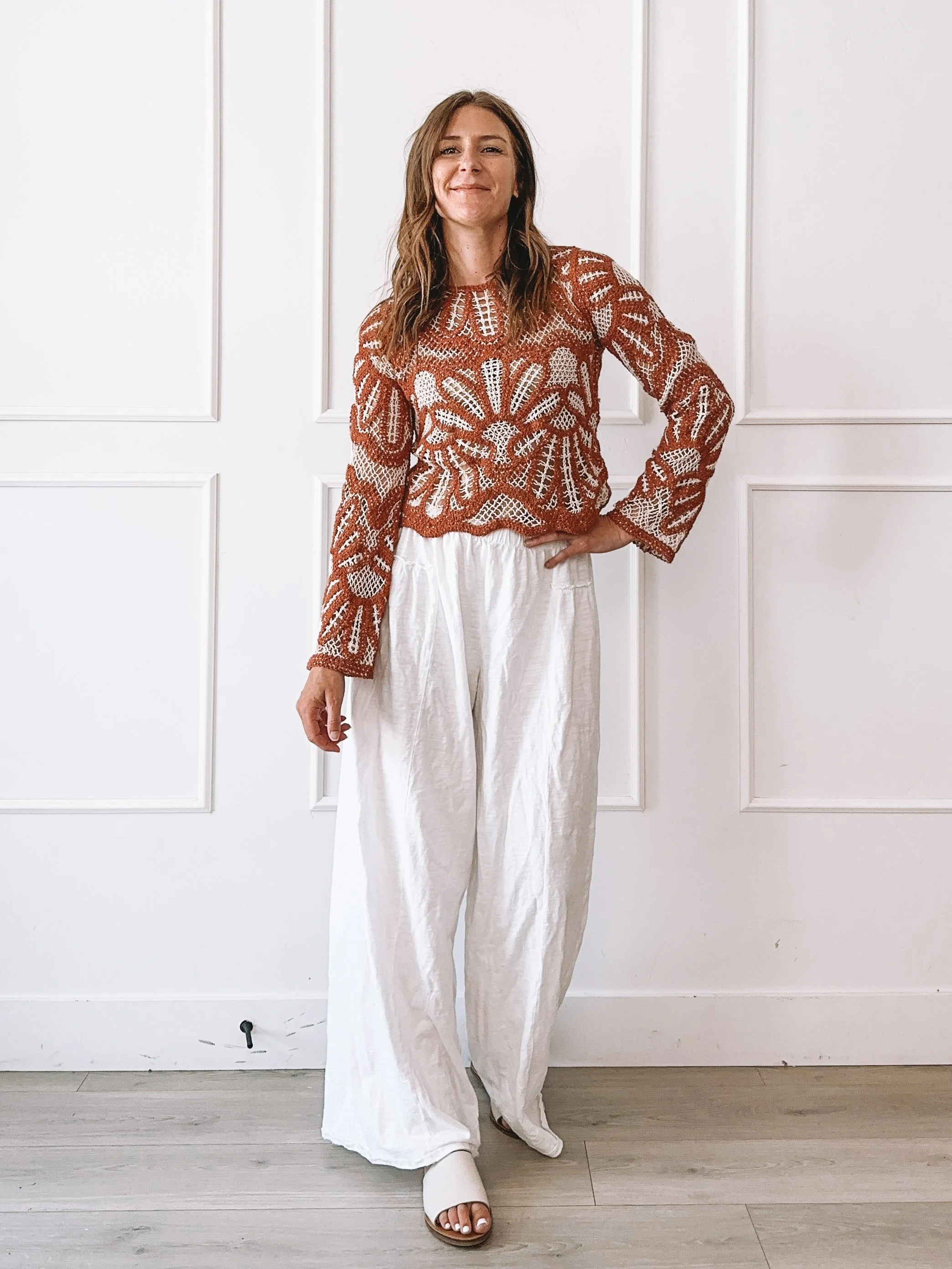Woman wearing a rust crochet sweater styled for an easy everyday summer look.