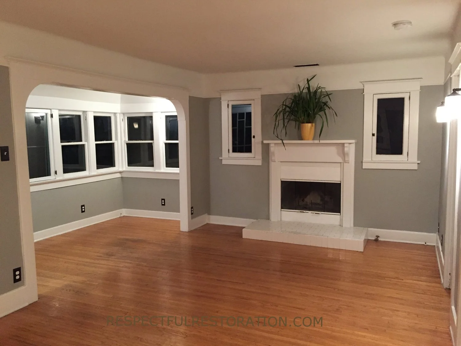 Interior entry and living room with restored original floors windows and plaster.