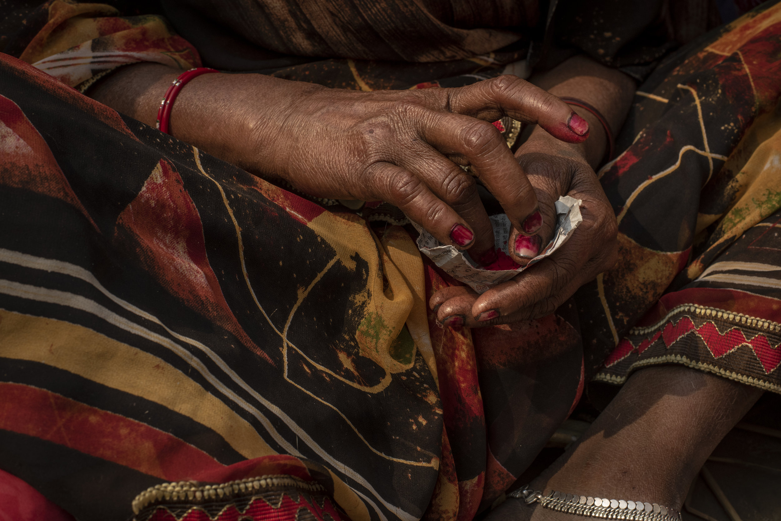 Woman prepares colored pigment to apply a bindi to her forehead