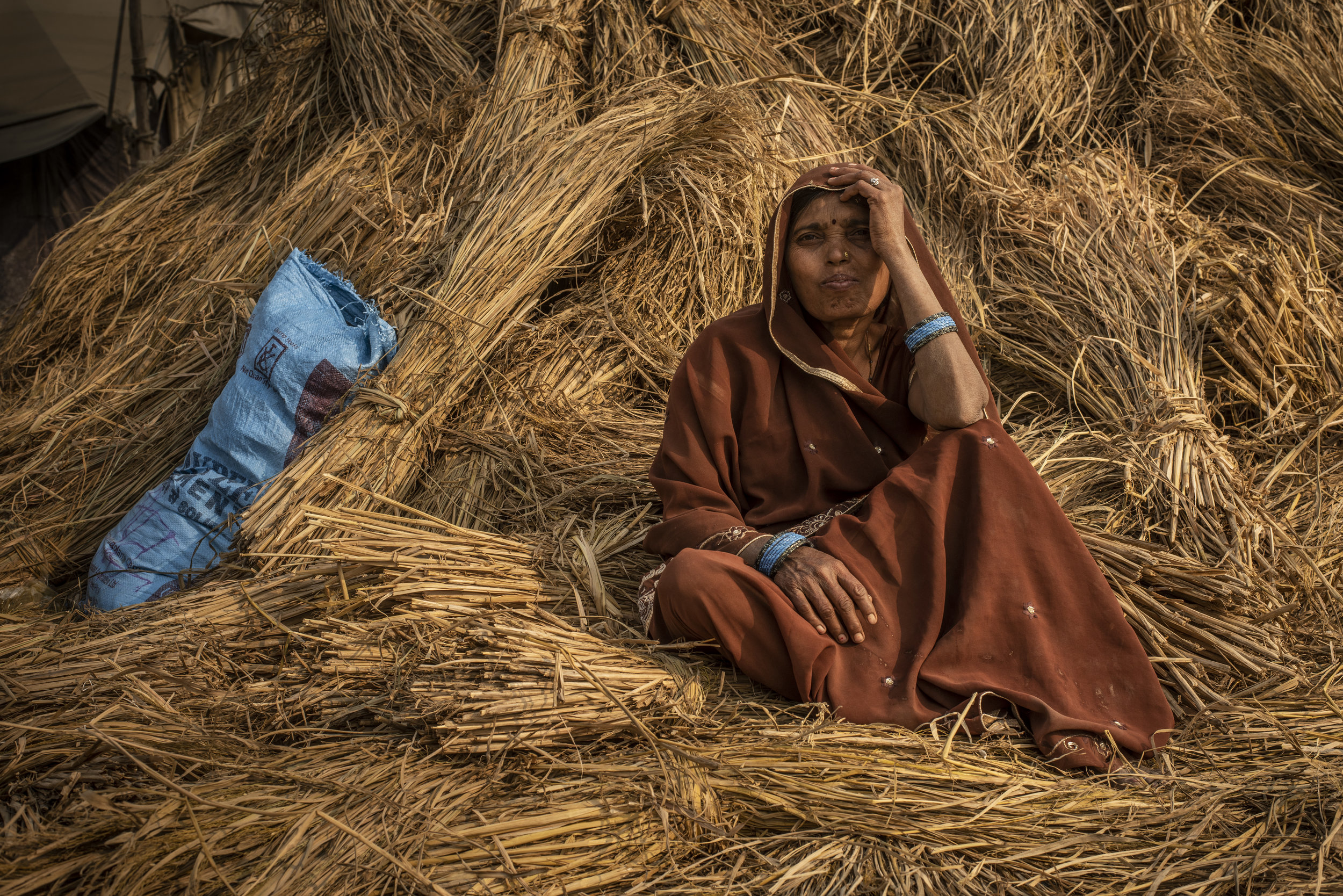  Woman rests on a bale of hay. 