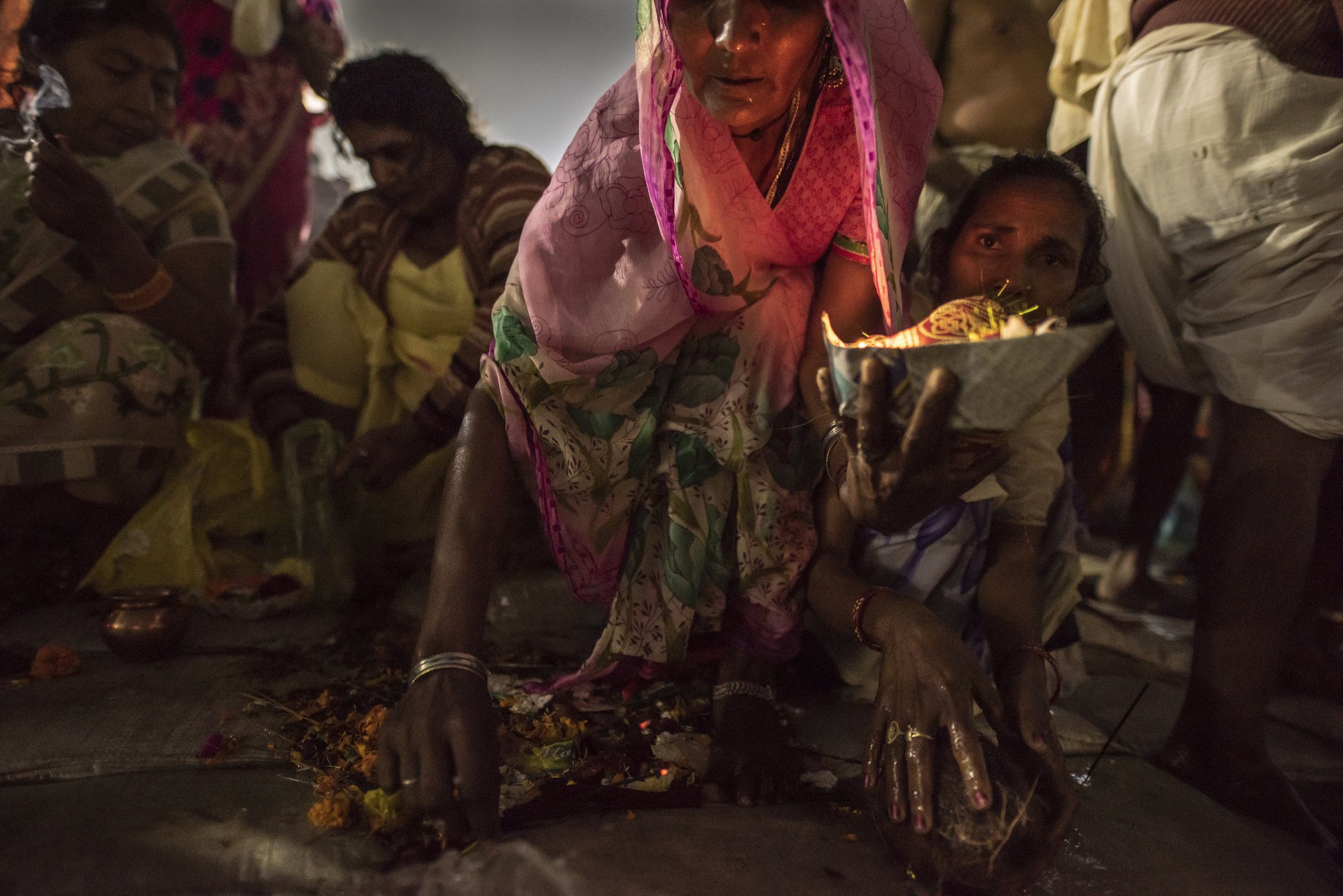 Women push through the throng to pray and offer fruit and flowers as pooja