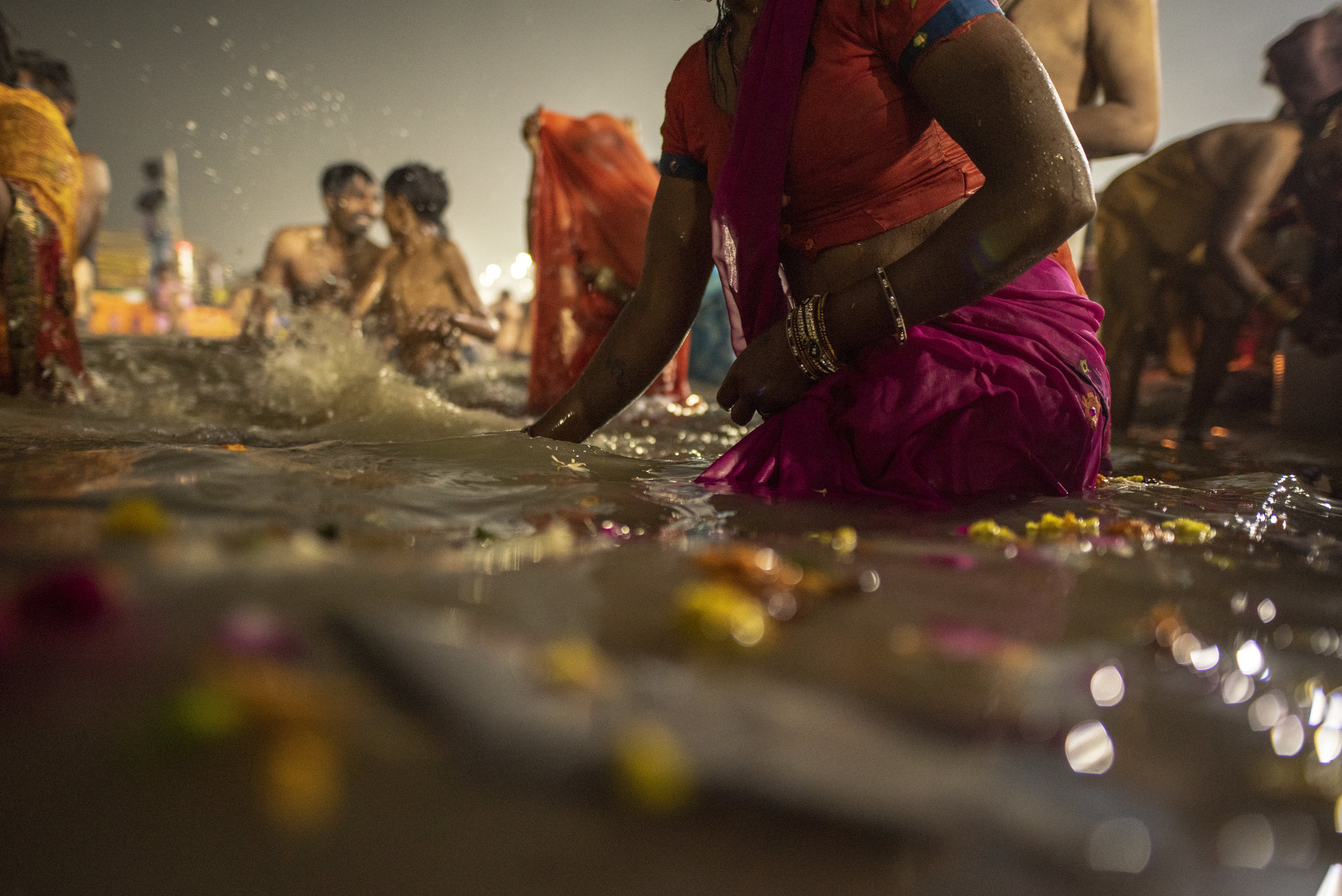Petals float in the Ganges as men and women gather to bathe