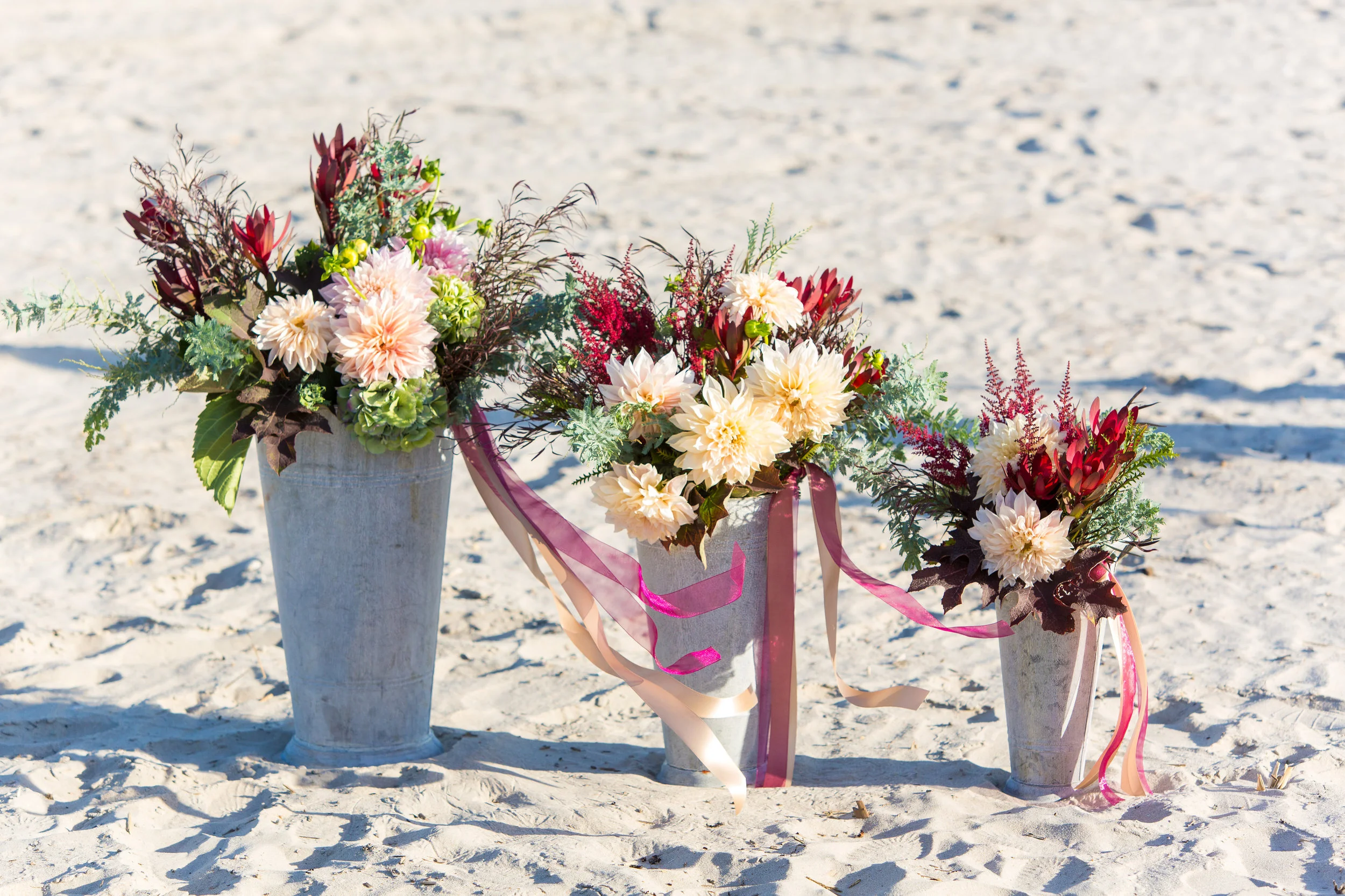 These buckets have never let us down for beach weddings. The buckets themselves are casual enough on their own that we can go all out in packing them full of lush arrangements of flowers. For Jenna and Jon's wedding, we used huge dahlias, astilbe, hydrangea, greenery and leaves for bright colorful designs, and the ribbon tails gave such pretty movement in the breeze. 