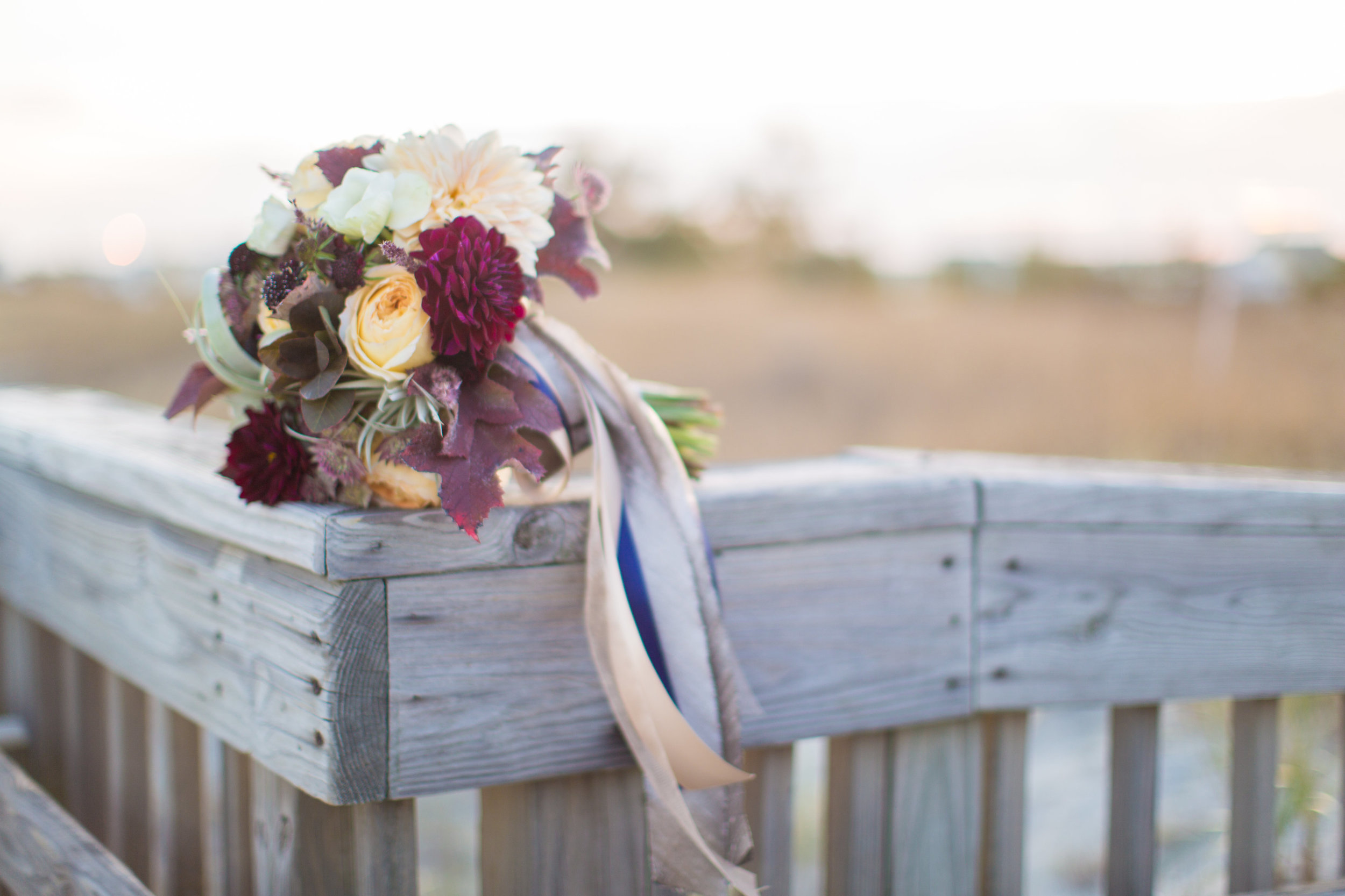 Jenna's bouquet was a staff favorite, made with airplants, burgundy and white dahlias, roses, and seasonal leaves. We loved her trailing ribbon tails and range of color.