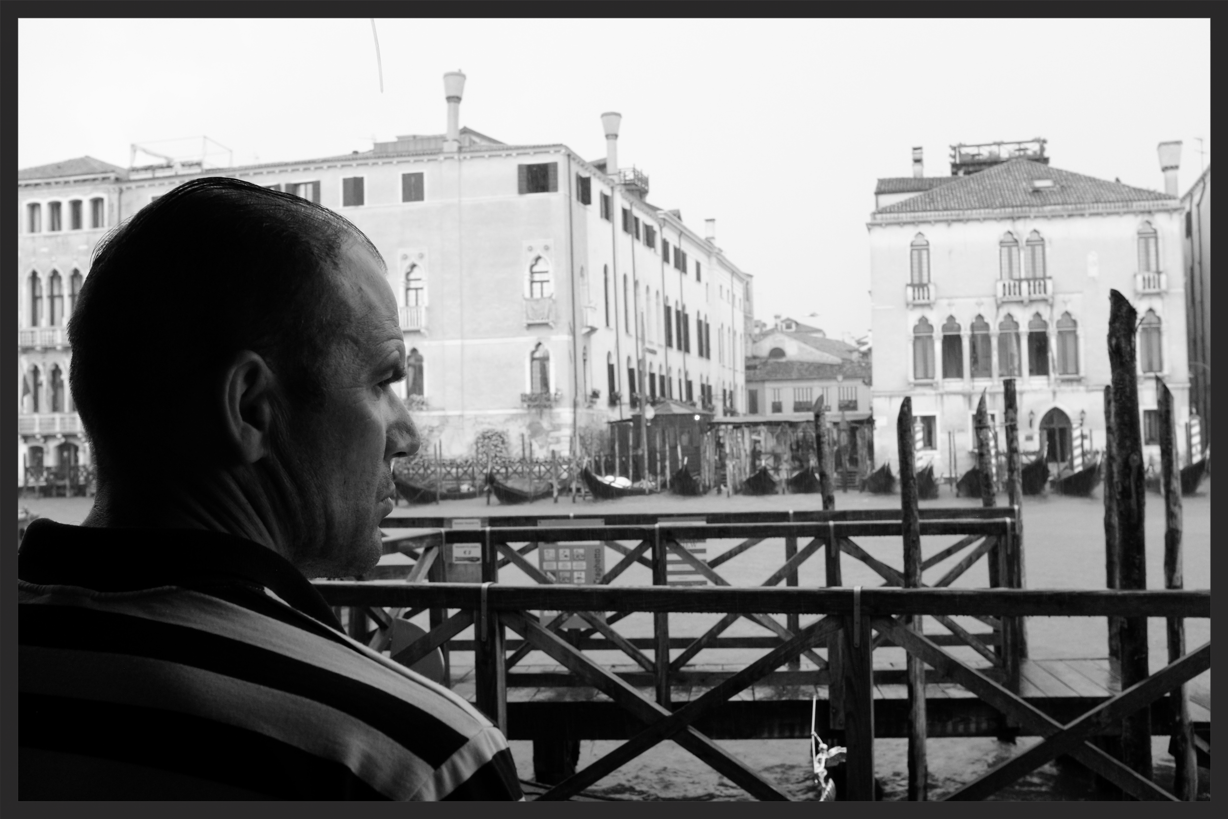 Inside the Rialto Market, a gondolier monitors his gondola during a storm.