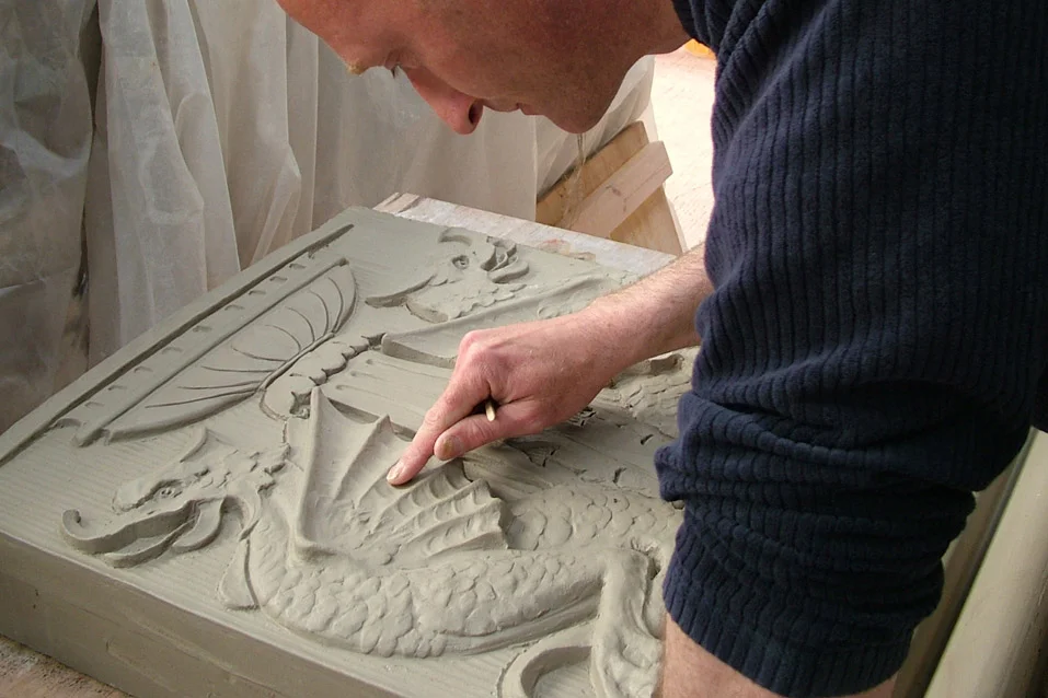 A person carving a detailed sculpture into a stone block.