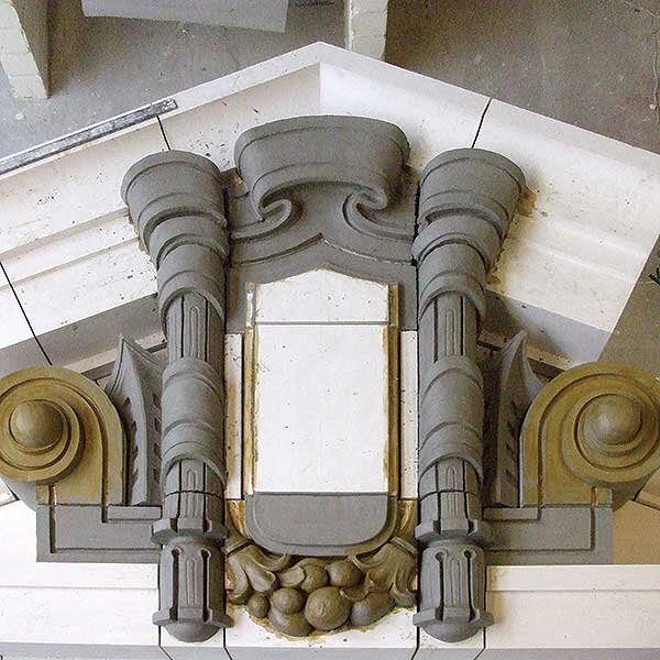 Ornate architectural detail with scrolls and decorative elements in gray and gold
