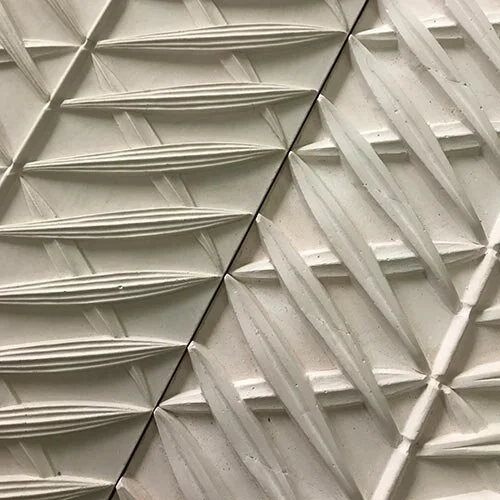 Close-up of a textured wall with a geometric pattern of repeating triangular and diamond-shaped elements.