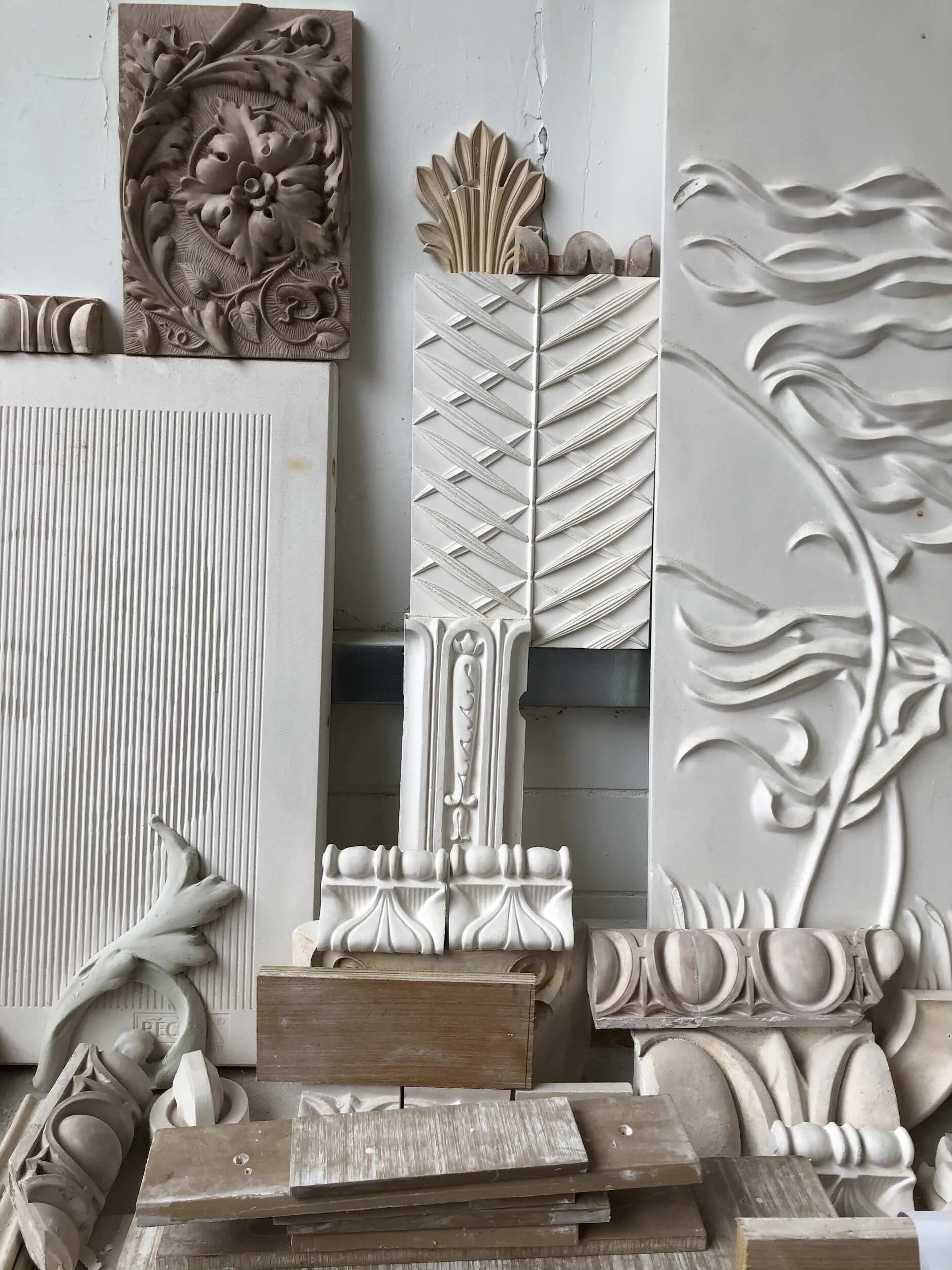 Various decorative wood carvings and moldings leaning against a wall.