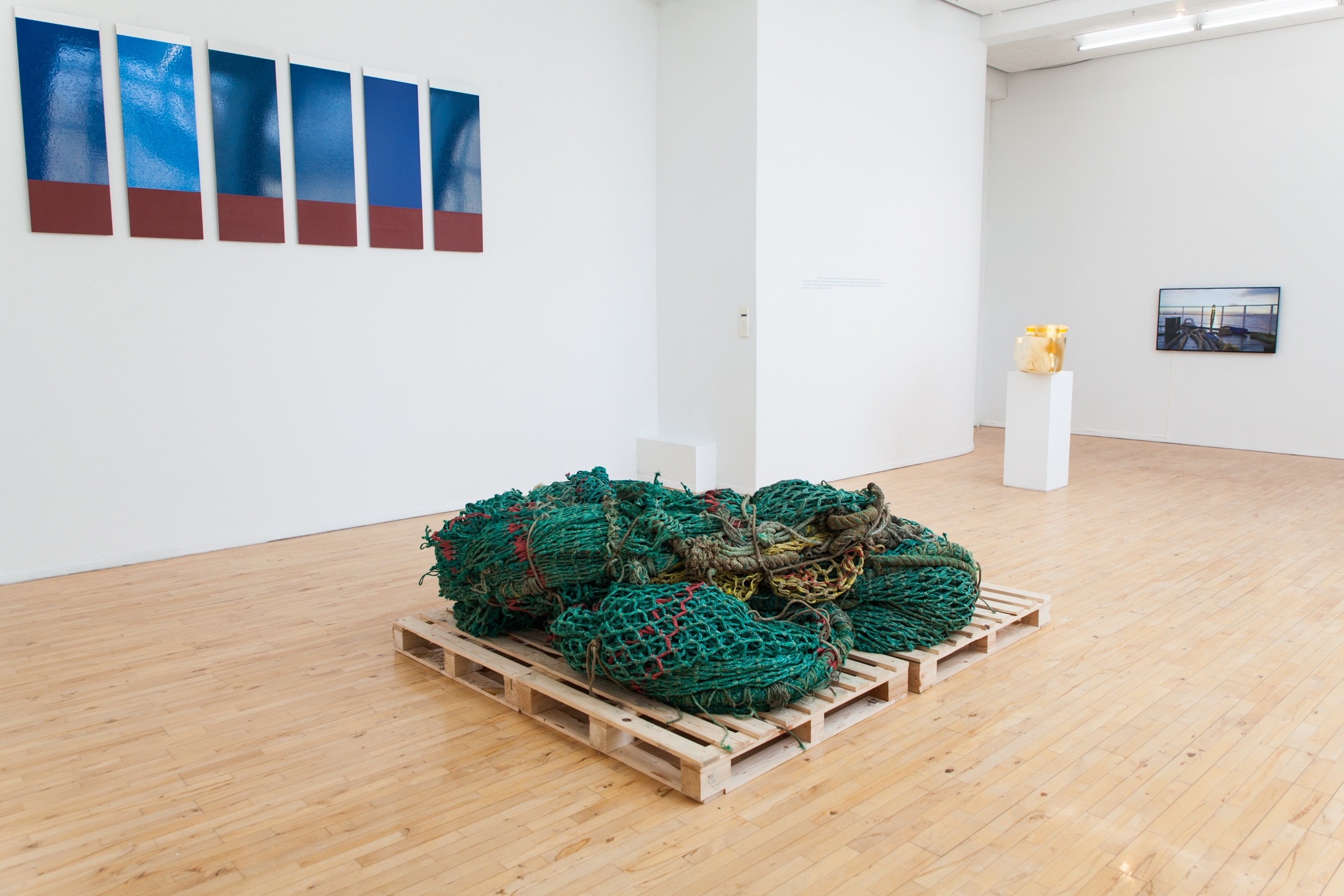 Installation view. Part of the 12 paintings, the net heap, the 'Goldship' sculpture, the inscription from Allan Sekula and the video 'Material Puffin' on a loop on the flatscreen monitor. Photo: Dennis Helm