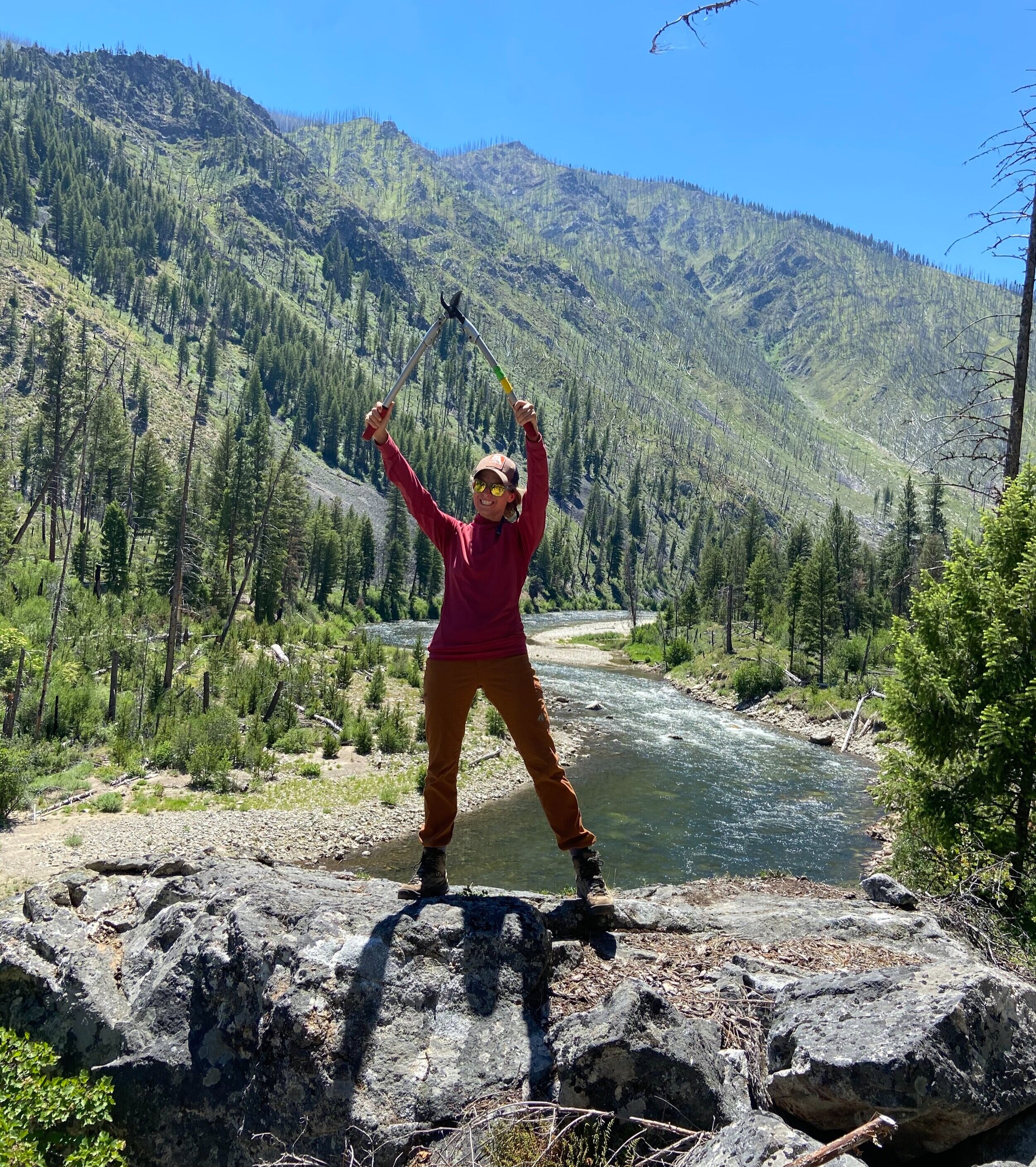 Volunteer, Gretchen Arguedas, standing on a rock outcropping over the Middle Fork of the Salmon River after lopping a dense section of trail #001. 