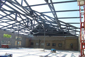 Fitness Center: A complicated geometry of hips and valleys made this a challenging project for our drafting department. Creating a 3D model of the entire framing ensured that every piece of steel fit to amazing precision. The site conditions created another challenge for us. A small jobsite with limited storage space, an adjacent building open for public use and large components for the roof trusses required deliveries be carefully coordinated and well planned. The configuration of the roof framing required two cranes. While one crane held the main truss in position the second crane placed the adjoining trusses stabilizing the entire system. The job was completed on time with a high level of safety and no incidents or accidents.