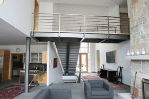 Mequon Residence: The design of this contemporary home incorporated a clean irregular shaped stair that seems to have its treads floating in space. This was accomplished by using a single steel tube for the support stringer and steel bent plates that formed the risers and blue stone tread supports. Every angle viewed of the stair provides a unique independent perspective. The structural steel bridge on the second floor and the stainless steel railings harmonize with their surroundings.