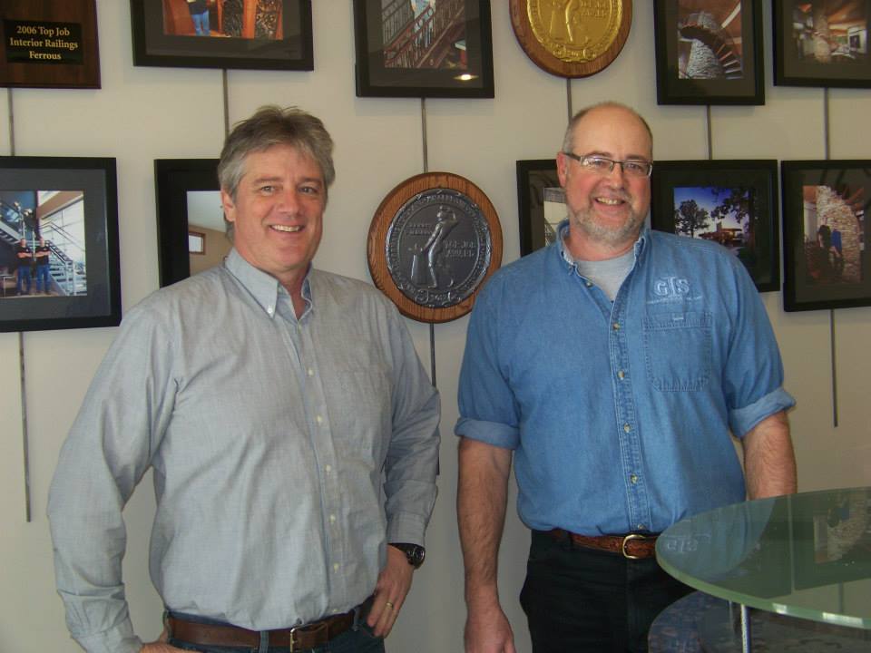 Owners Ken and Dave Gutbrod stand next to one of the bronze medals awarded to Germantown Iron & Steel from the National Ornamental & Miscellaneous Metals Association (NOMMA). Germantown Iron & Steel has received two gold (2006 and 2012), one silver (2019), and two bronze (2004 and 2005) Top Job Awards from NOMMA.